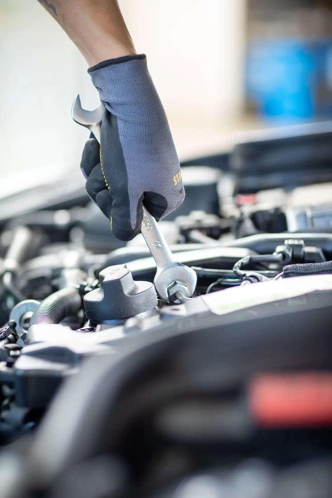 STANLEY FMMT13069-0 wrench in use on car engine, mechanic wearing black gloves, product photography.