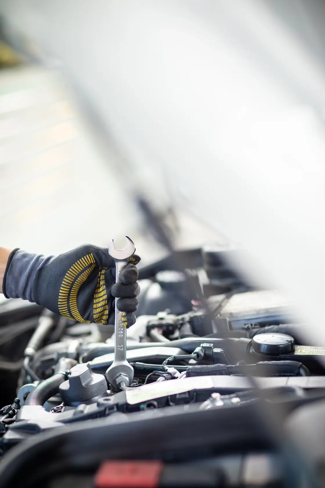 STANLEY FMMT13072-0 wrench held by gloved hand, working on car engine, vertical angle.