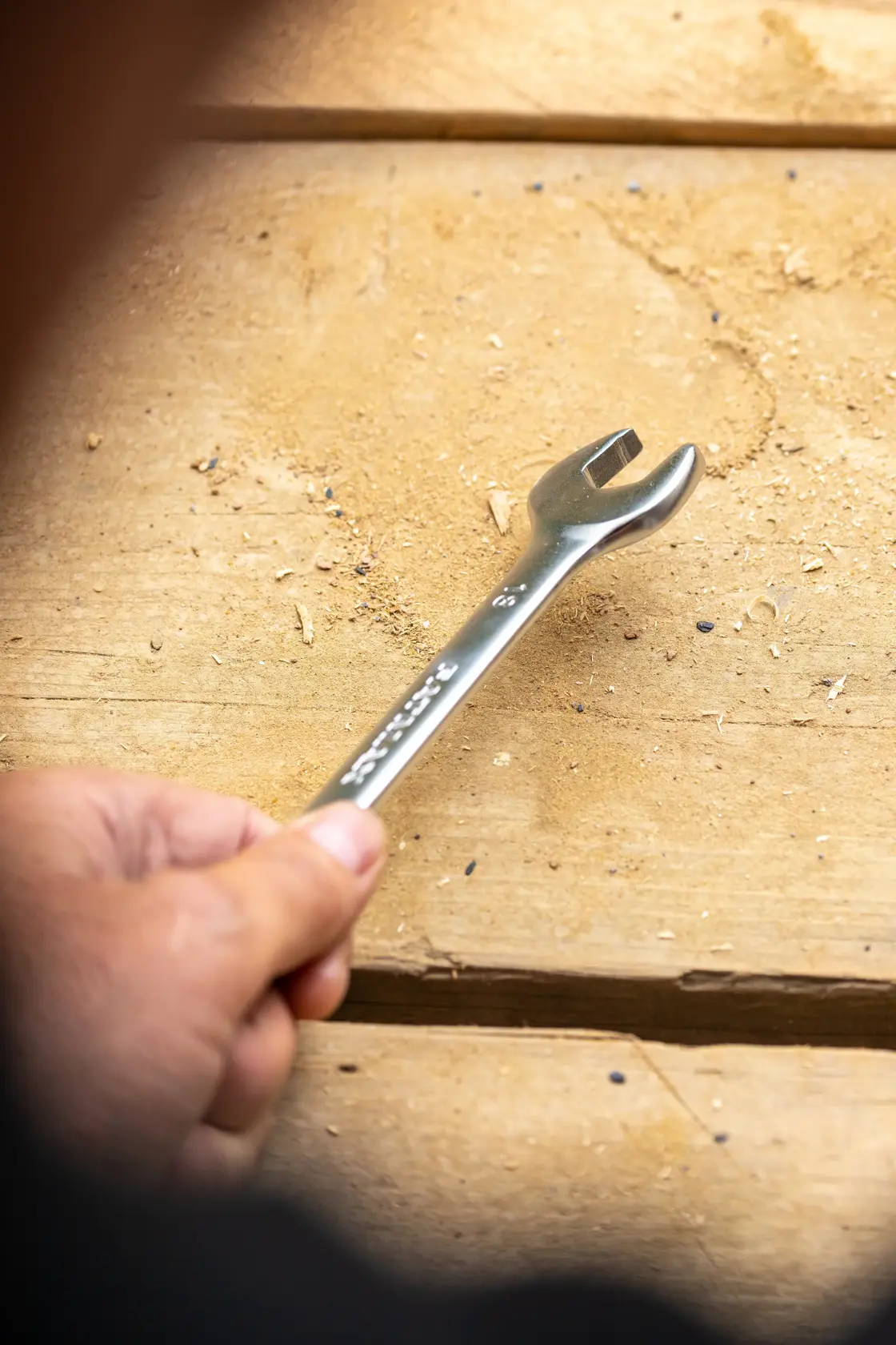 Stanley FMMT13072-0 wrench held in hand, photography on wooden surface with scattered wood shavings.