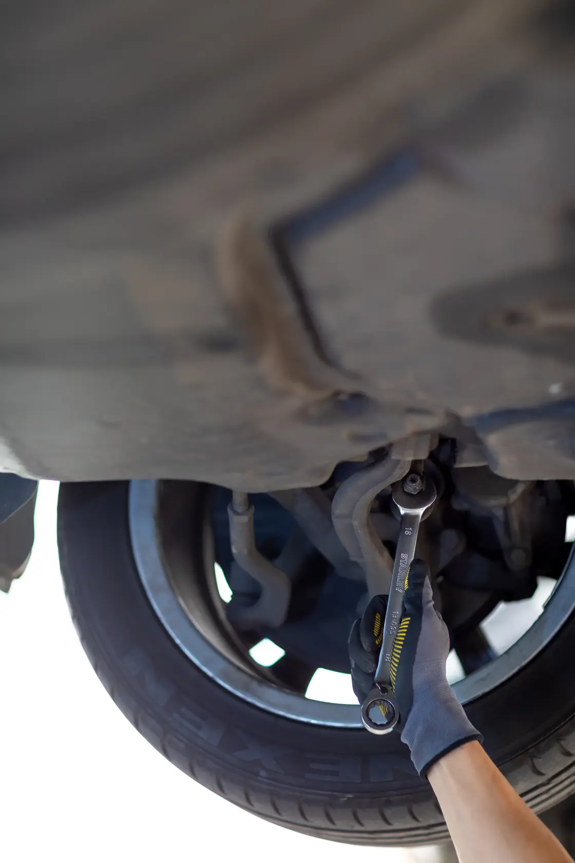 Photo of STANLEY FMMT13087-0 ratcheting wrench in use under car near wheel.