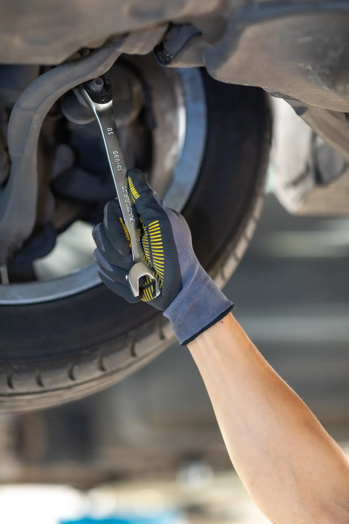 Photo of STANLEY FMMT13094-0 wrench in use by gloved hand repairing car undercarriage, automotive context.