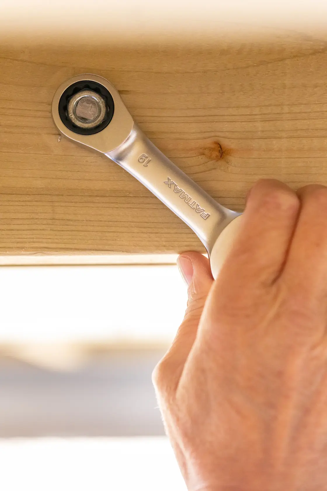 STANLEY FMMT13097-0 ratcheting wrench tightening bolt on wood beam, close-up hand action.