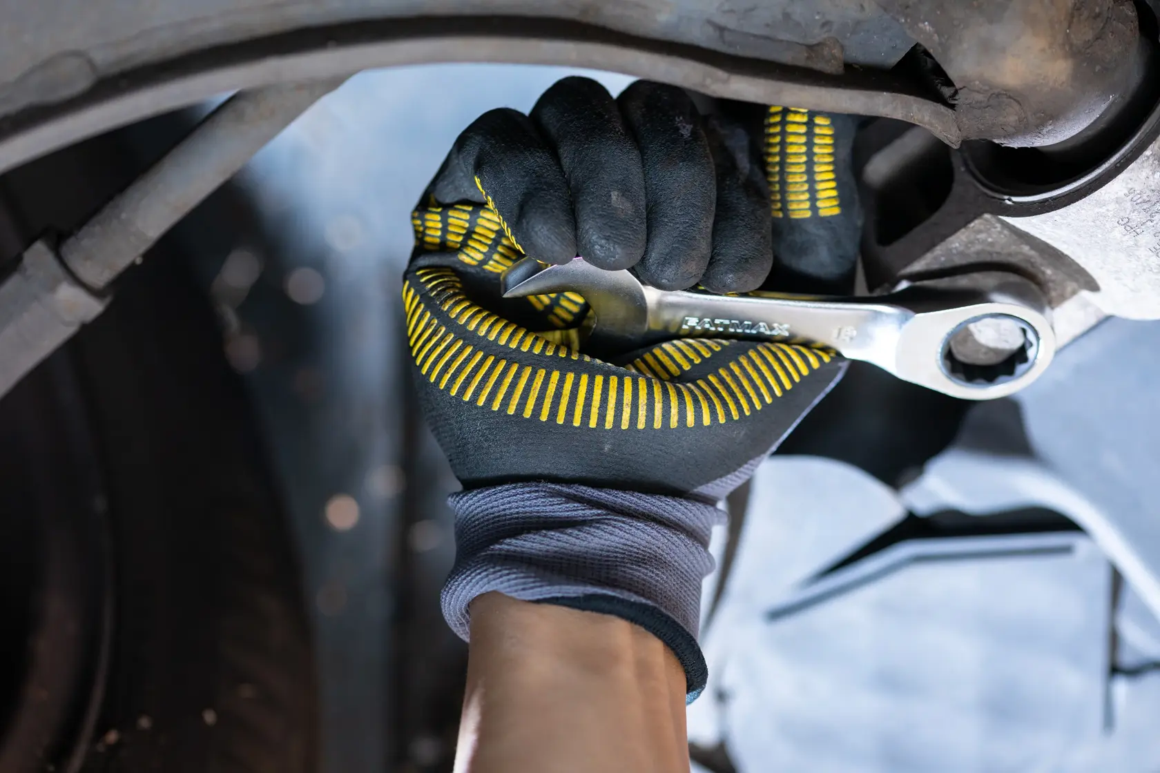STANLEY FMMT13113-0 wrench being used with glove, close-up of tool tightening bolt, automotive context.