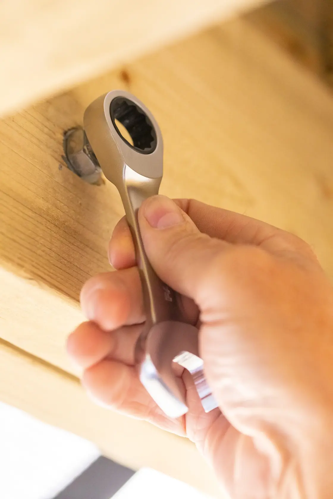 STANLEY FMMT13115-0 ratcheting wrench tightening a bolt on wood, close-up hand holding tool.