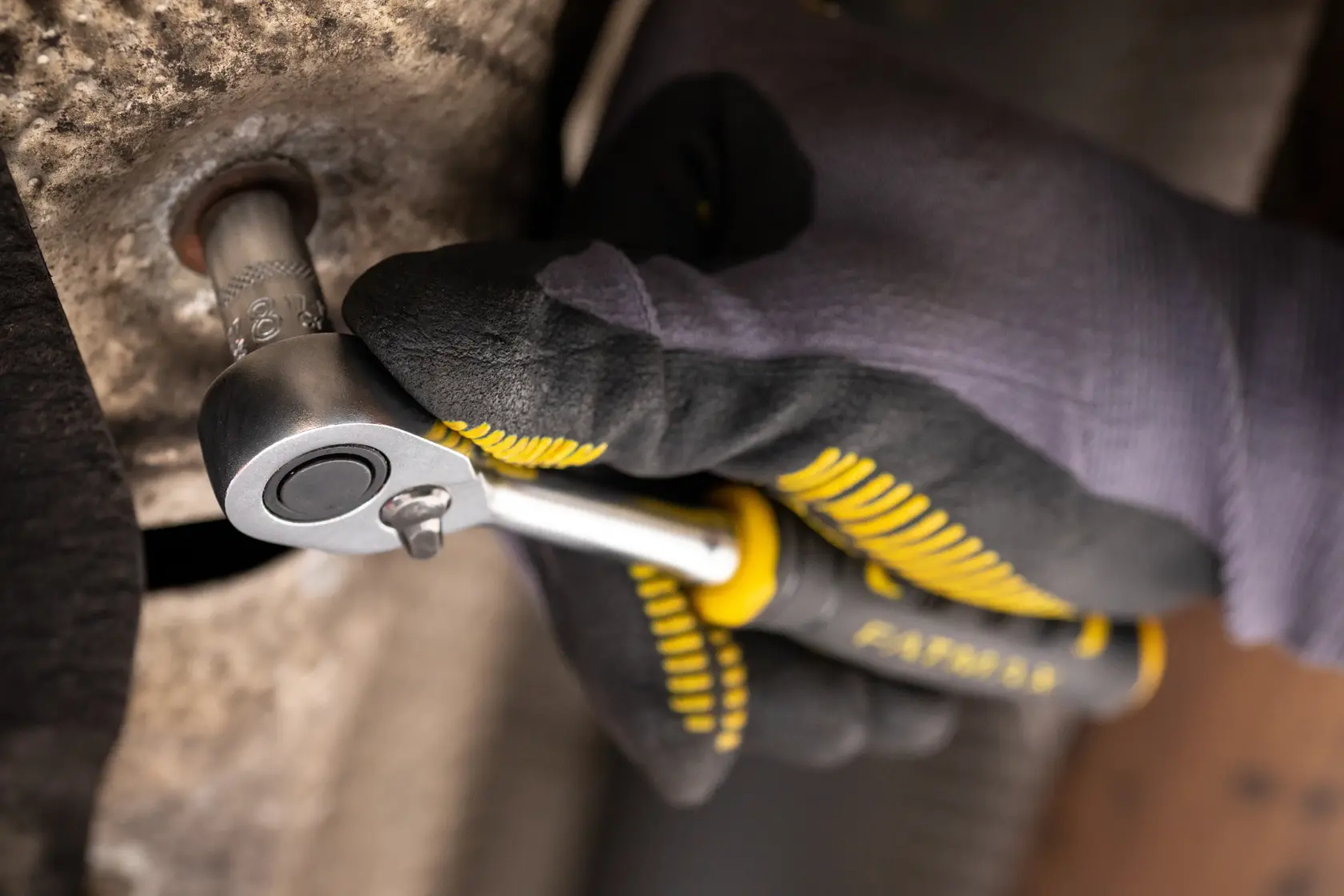 Photo of STANLEY FMMT17185-0 ratchet wrench in gloved hand tightening a bolt, close-up view.