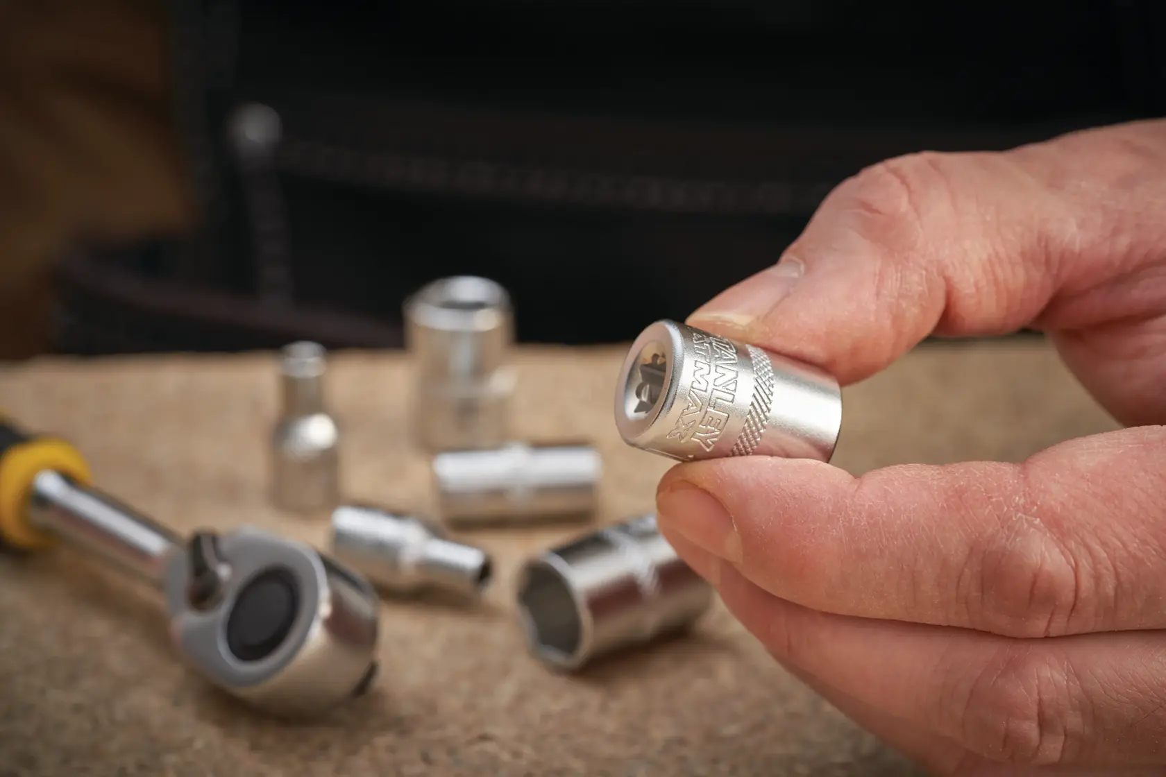 Photo of STANLEY FMMT17190-0 socket held in hand, with other sockets and ratchet tool on a work surface.