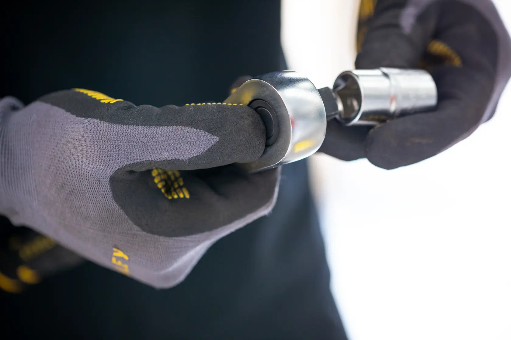 Photo of STANLEY FMMT17210-0 socket attachment held by gloved hands, close-up view.
