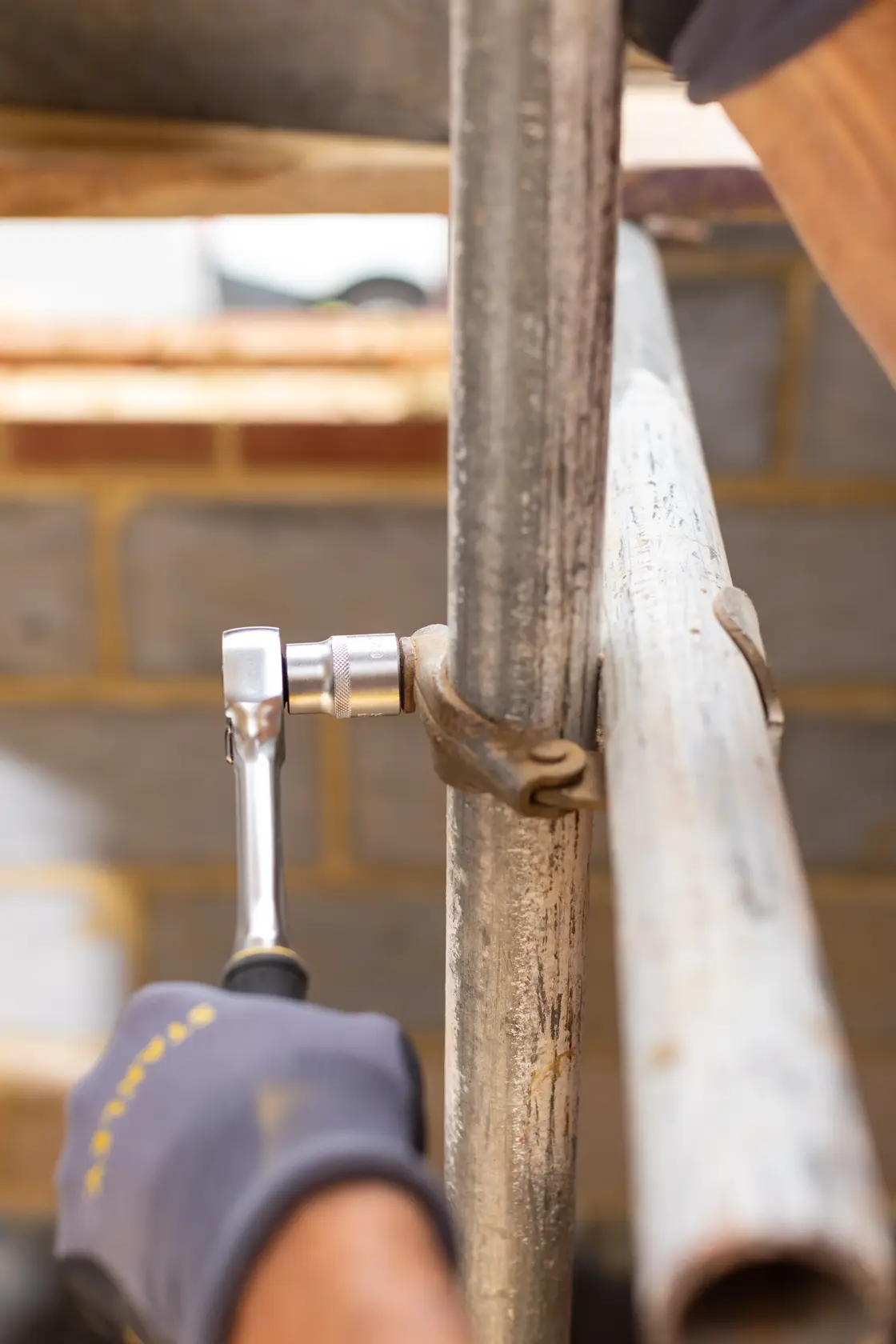 STANLEY FMMT17246-0 ratchet wrench used on metal pipe clamp, close-up outdoor photography.