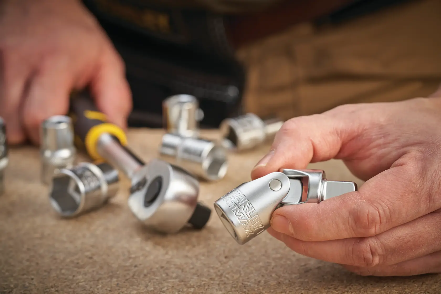 Photo of STANLEY FMMT17999-0 socket set with ratchet, hand holding silver socket, tabletop view.