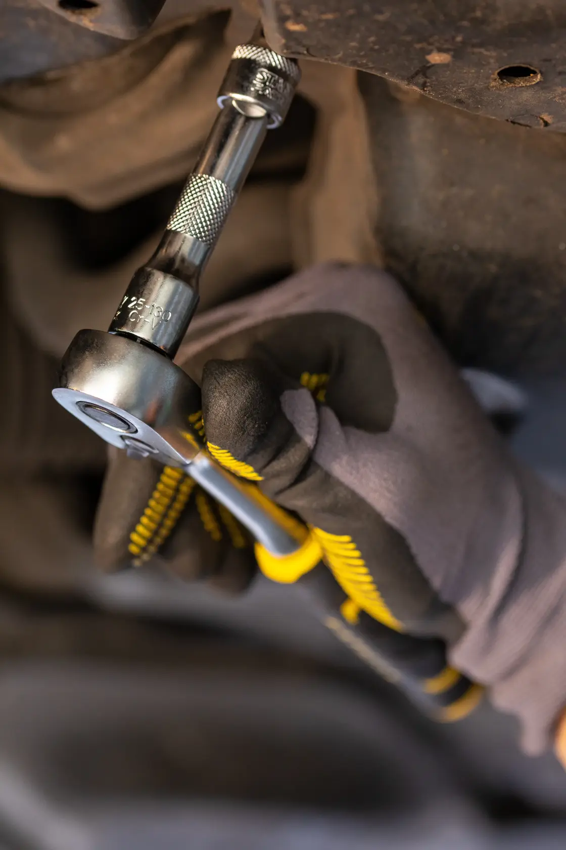 STANLEY FMMT25130-0 ratchet wrench used for automotive work, close-up of tool in gloved hand.
