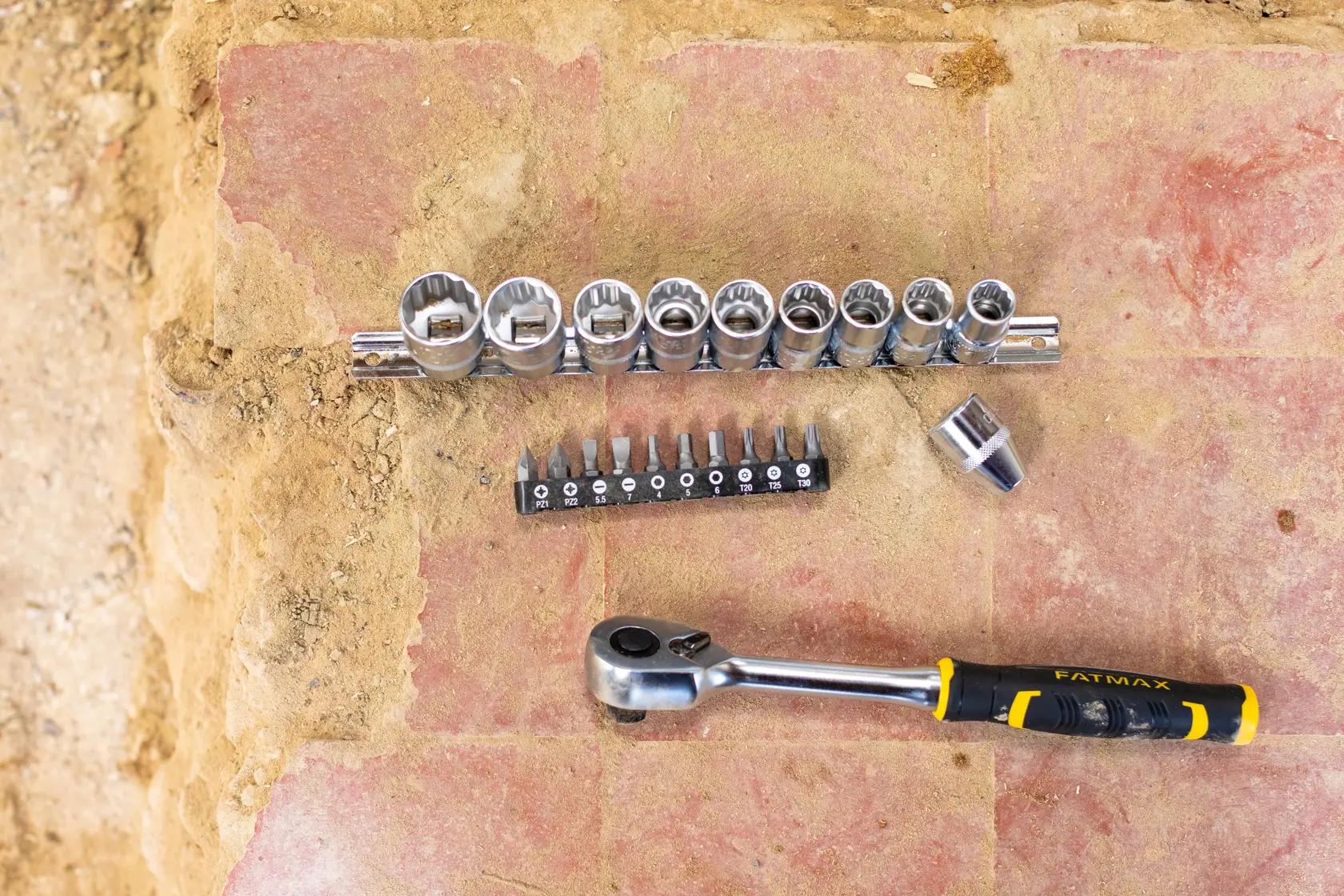 STANLEY FMMT82680-0 socket and bit set with ratchet handle, multiple sockets, and bits on a brick surface, top view.