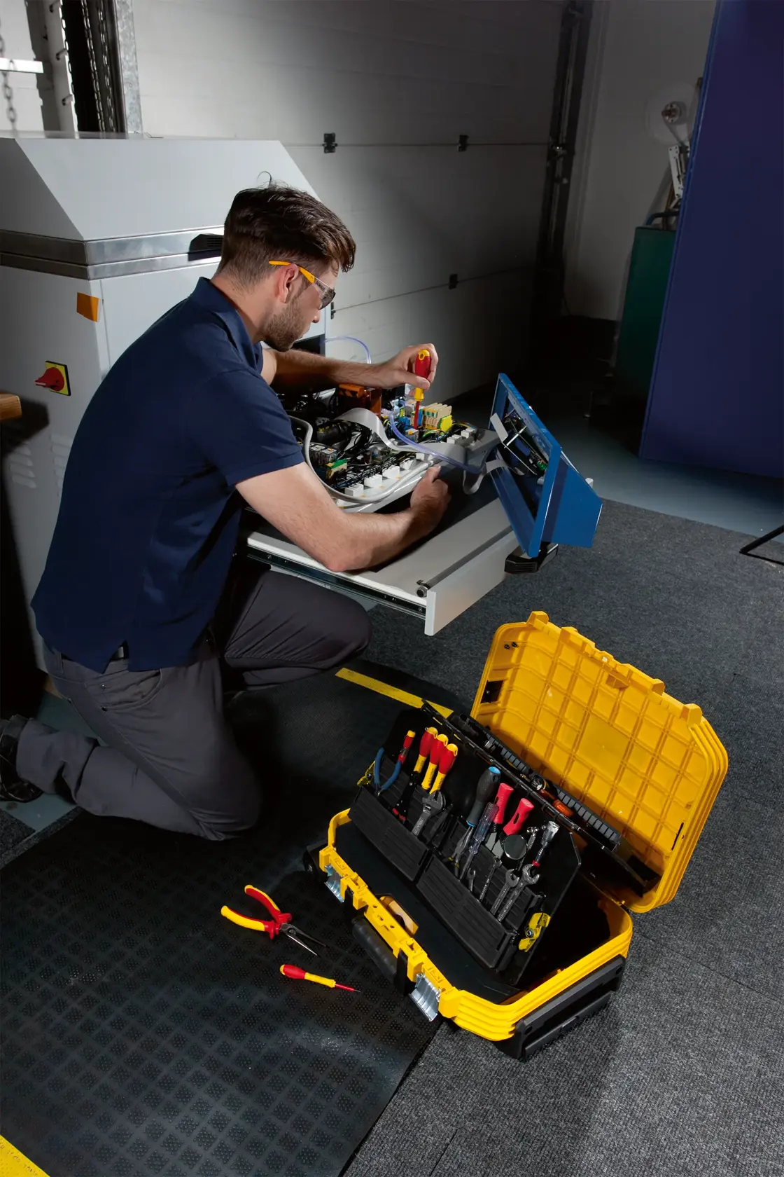 STANLEY FMST1-71943 toolbox open on the floor with assorted hand tools, technician working nearby.