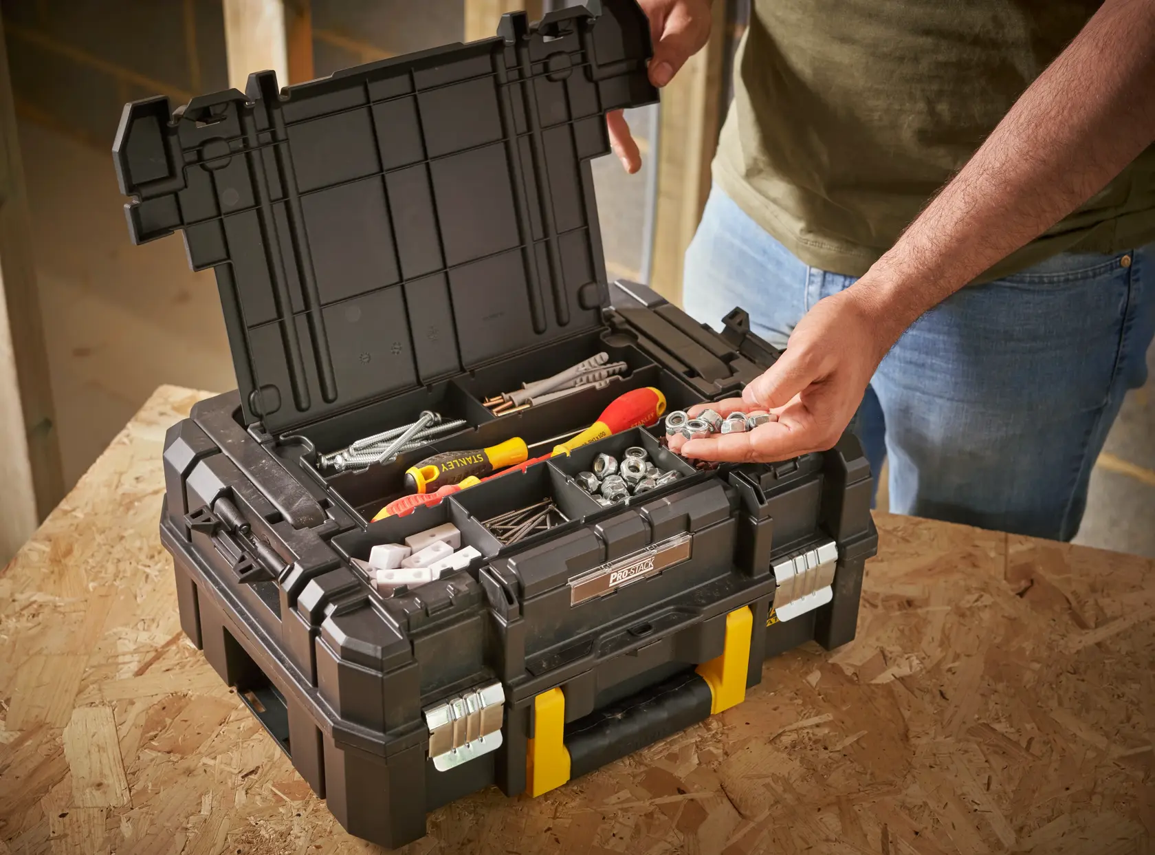 STANLEY FMST1-71967 toolbox with open lid, showing compartments with tools and hardware, on a workbench.