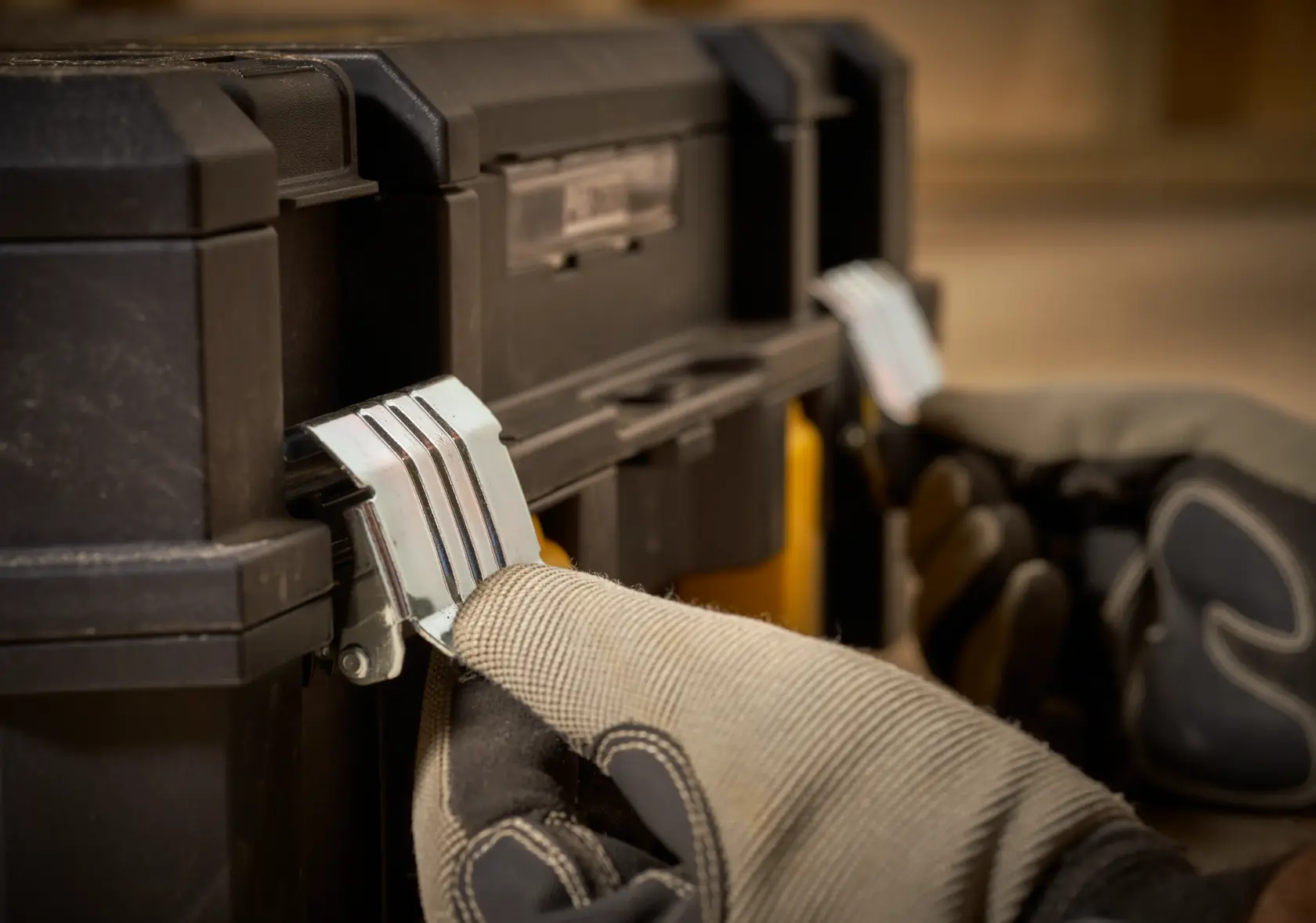 Photo of STANLEY FMST1-71967 toolbox latch being operated with gloved hands, close-up angle.