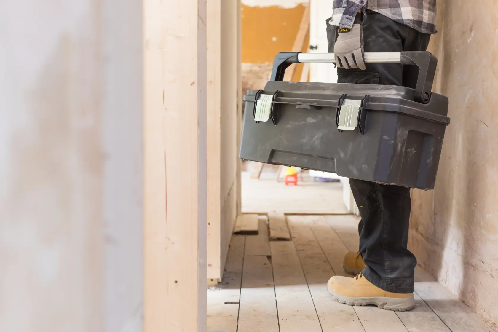 Photo of person holding STANLEY FMST1-75791 toolbox with handle in a construction site hallway.