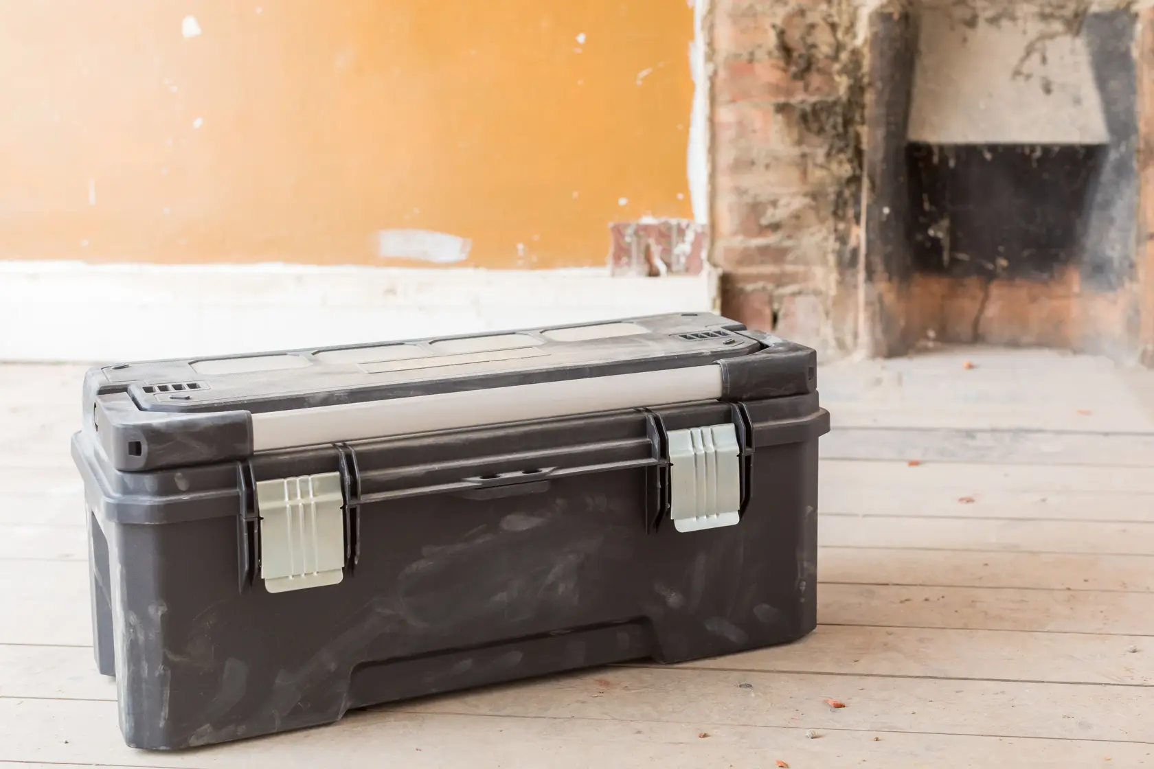 STANLEY FMST1-75791 black plastic toolbox with metal latches, front angle, placed on wooden floor.