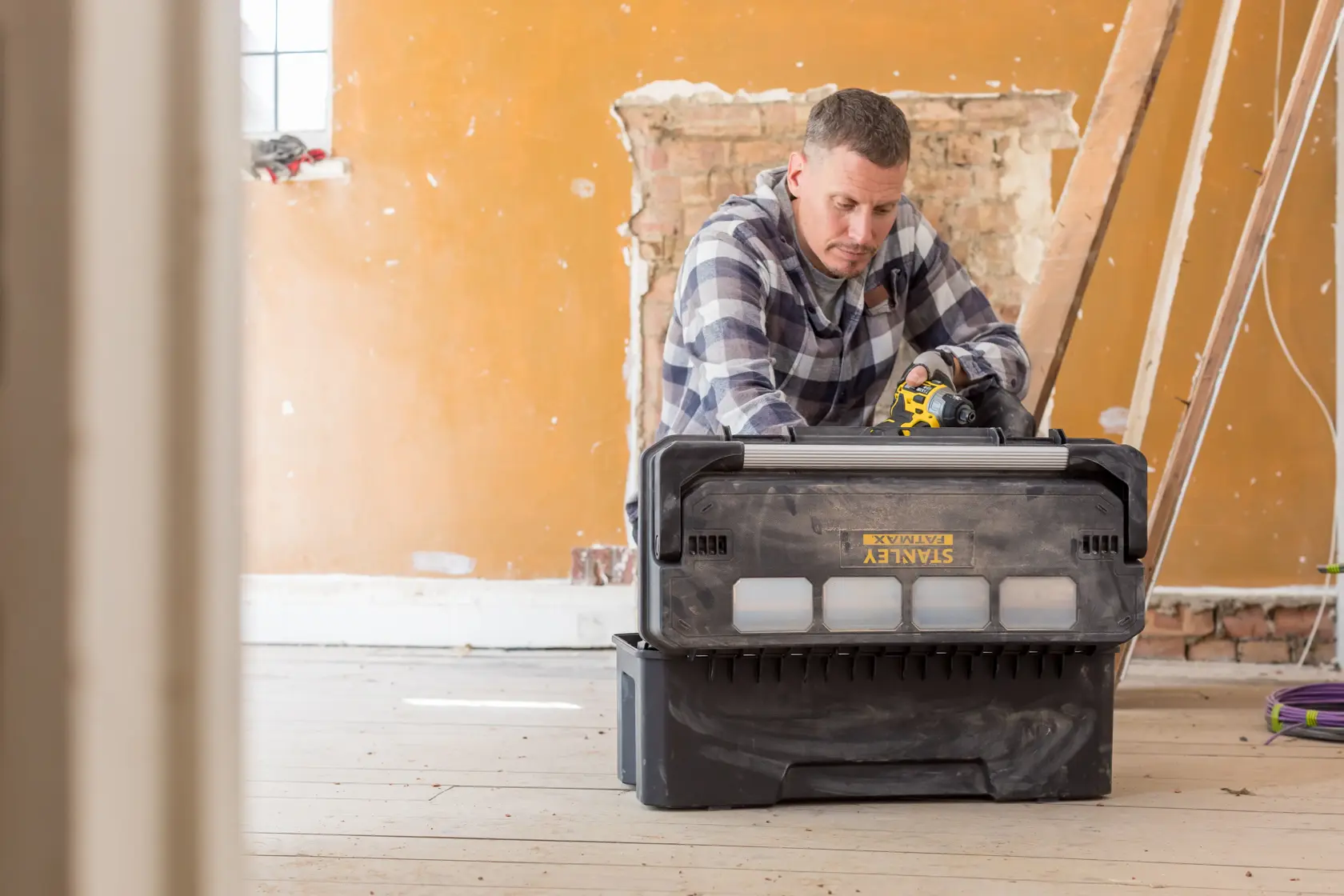 STANLEY FMST1-75791 modular tool storage box in use during renovation work, black and yellow exterior.