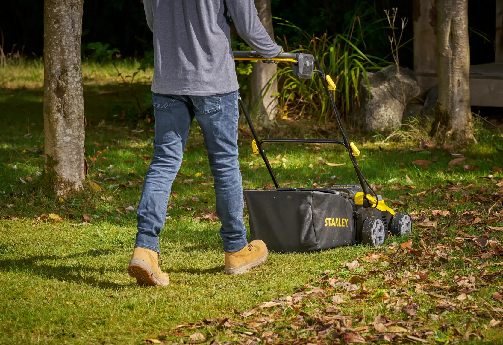 STANLEY SCOEP3801M2 lawn mower with black and yellow design in use on grass, rear side view.
