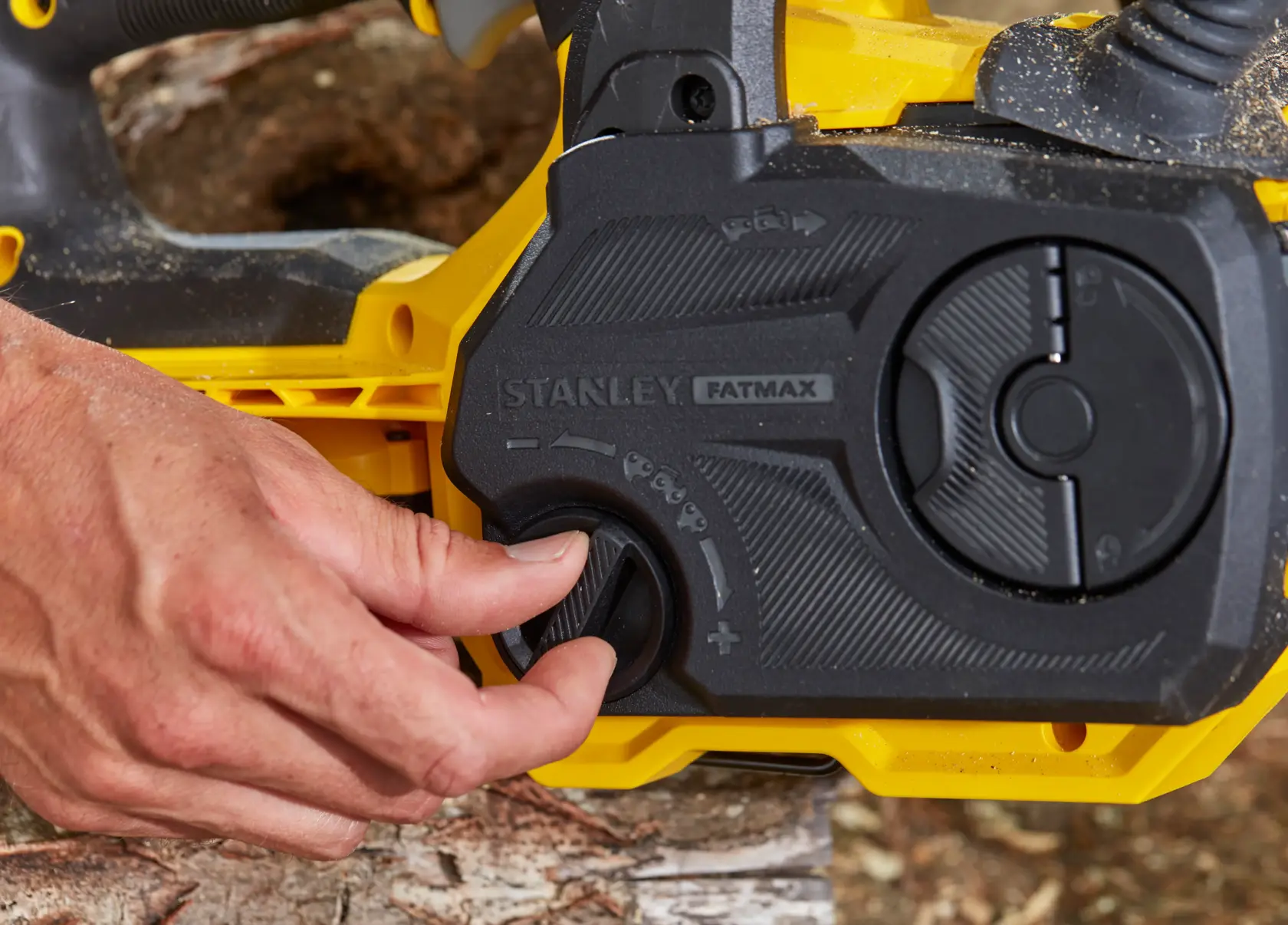 Photo of STANLEY SFMCCS630B chainsaw control panel, close-up of adjustment knob being turned.