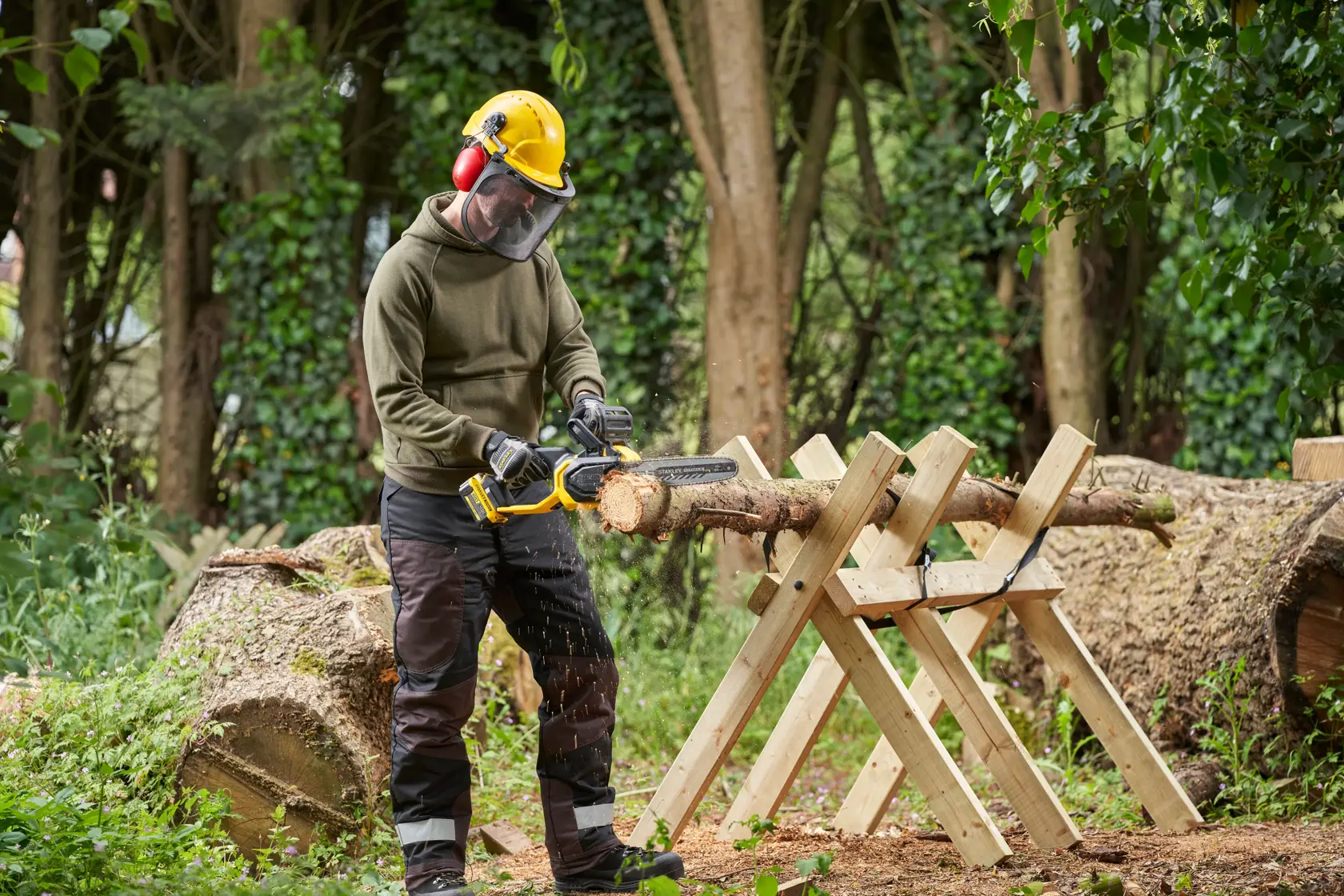 STANLEY SFMCCS730M1 chainsaw in use cutting a log outdoors with operator wearing safety gear.