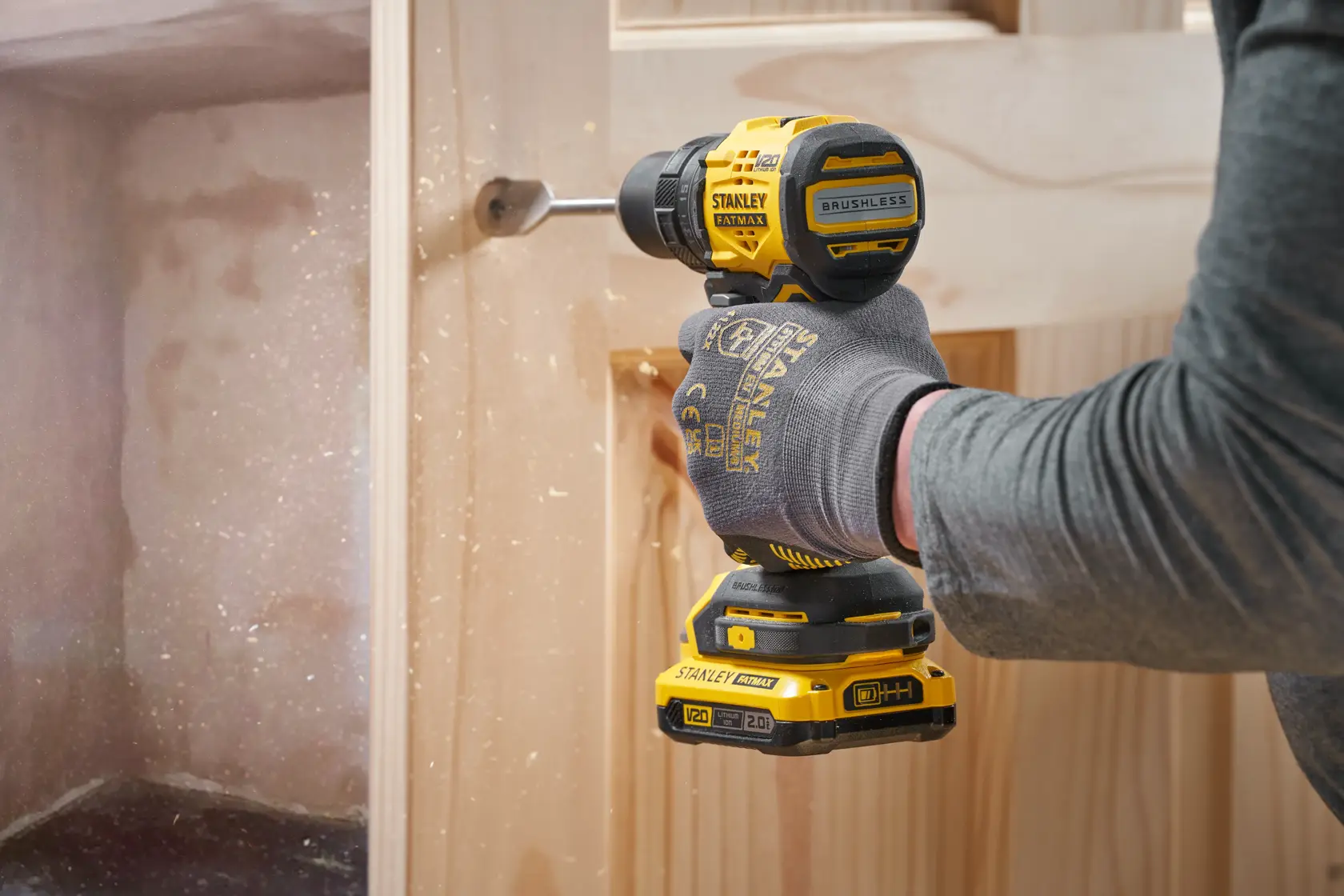 Photo of STANLEY SFMCD714D2T cordless drill in use drilling into wood, yellow and black design, close-up view.