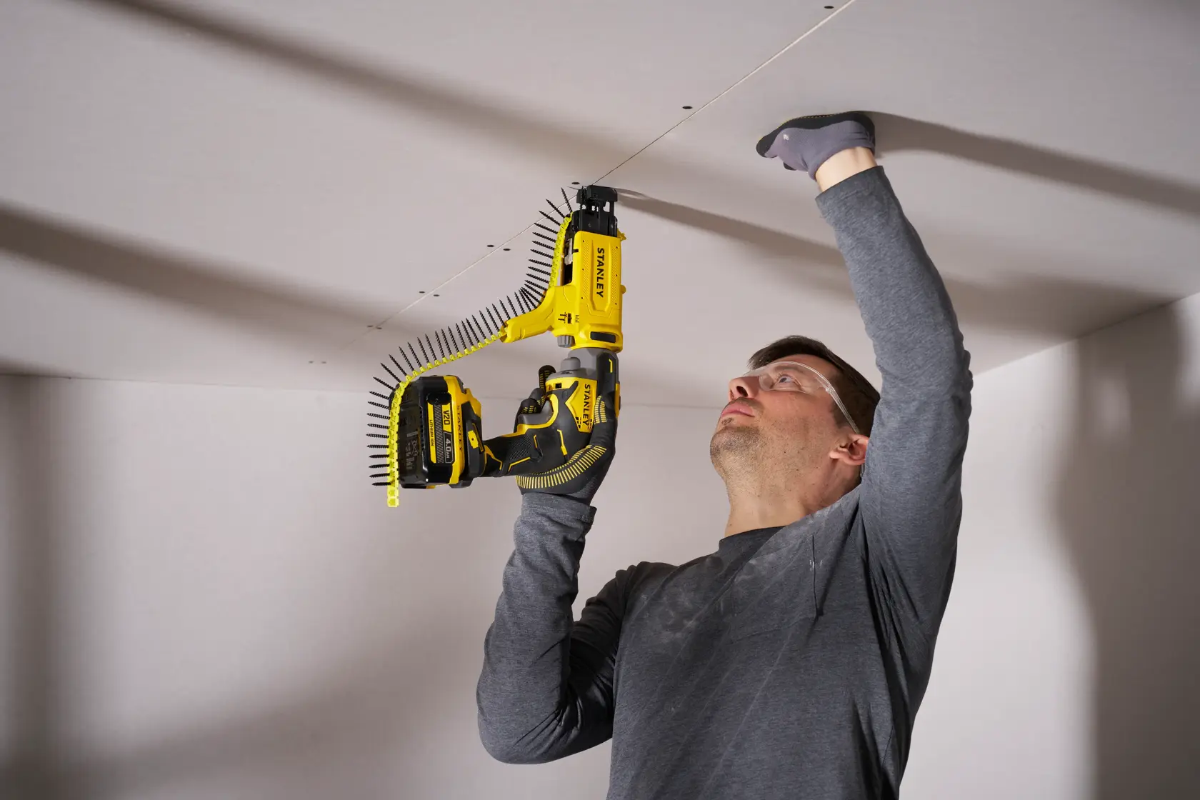 STANLEY SFMCF600B screw gun used for ceiling drywall installation, photo shows tool in action.