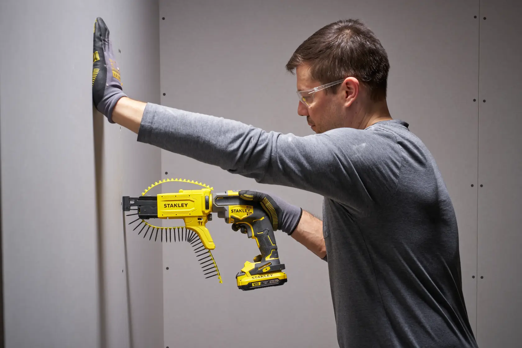 Photo of STANLEY SFMCF600D1S autofeed screw gun in use installing drywall, held by person wearing work gloves.