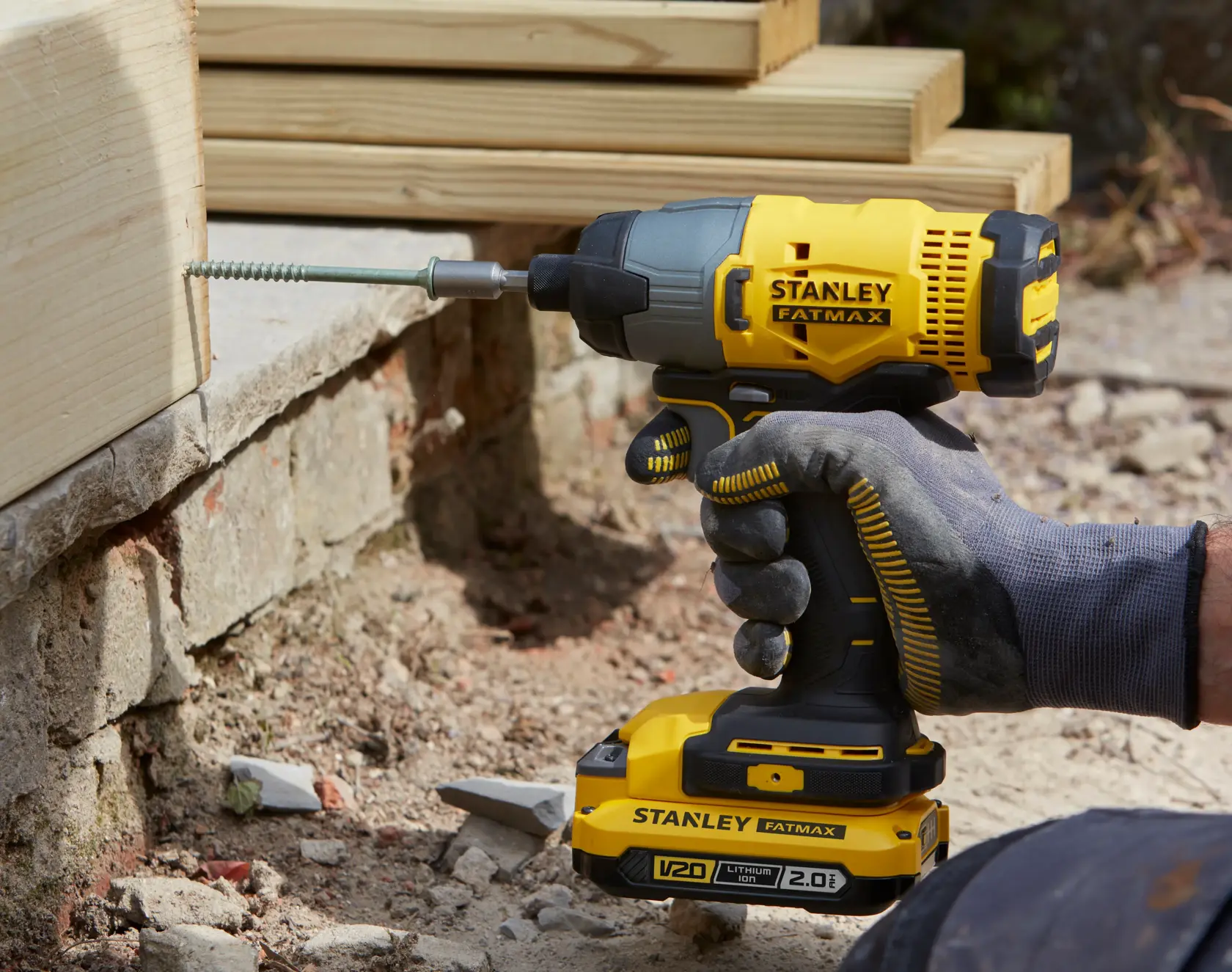 STANLEY SFMCK465D2S cordless impact driver in use driving screw into wood, showing battery and grip details.