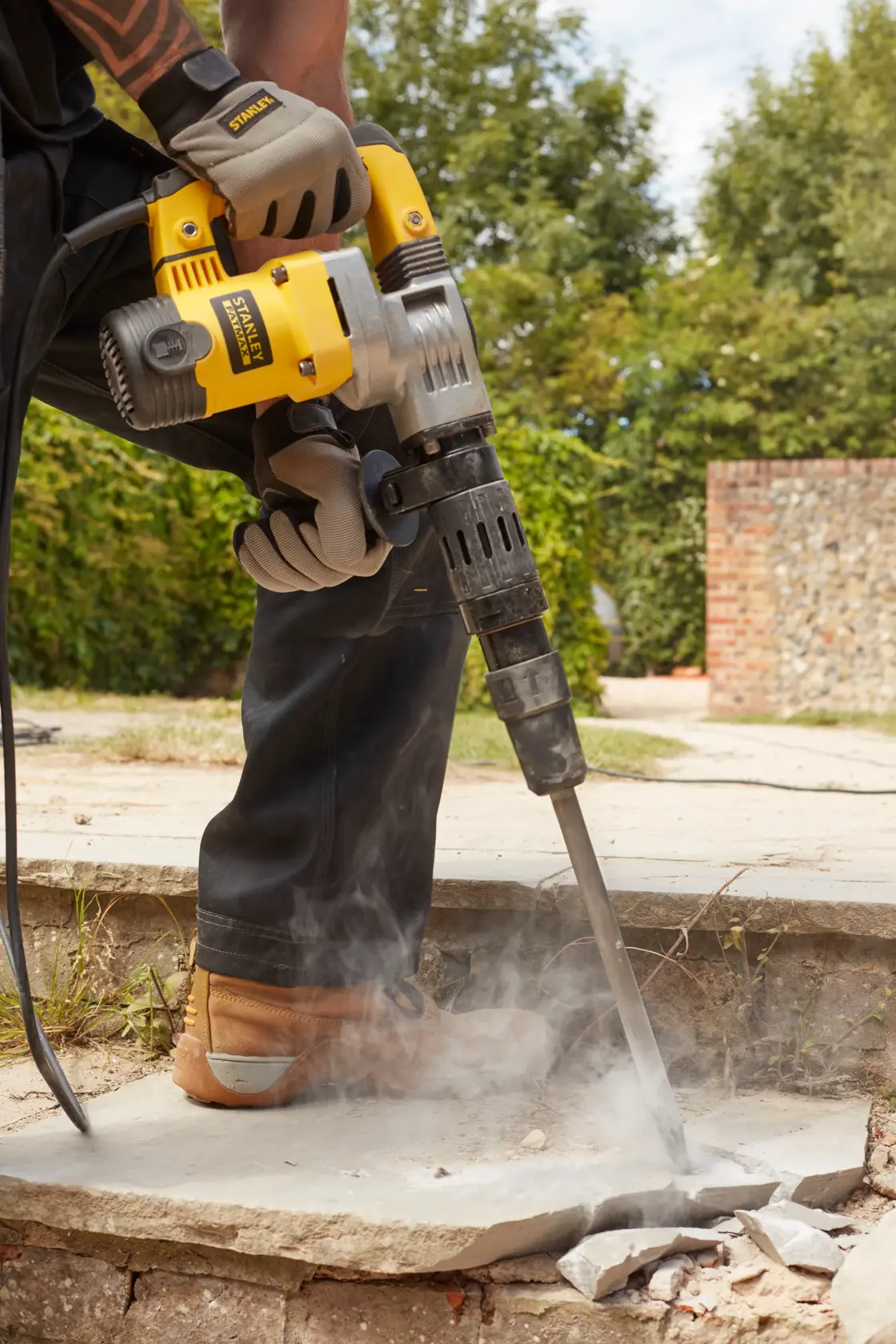 STANLEY SFMEH220K-QS rotary hammer breaking concrete outdoors, close-up view of tool in use.