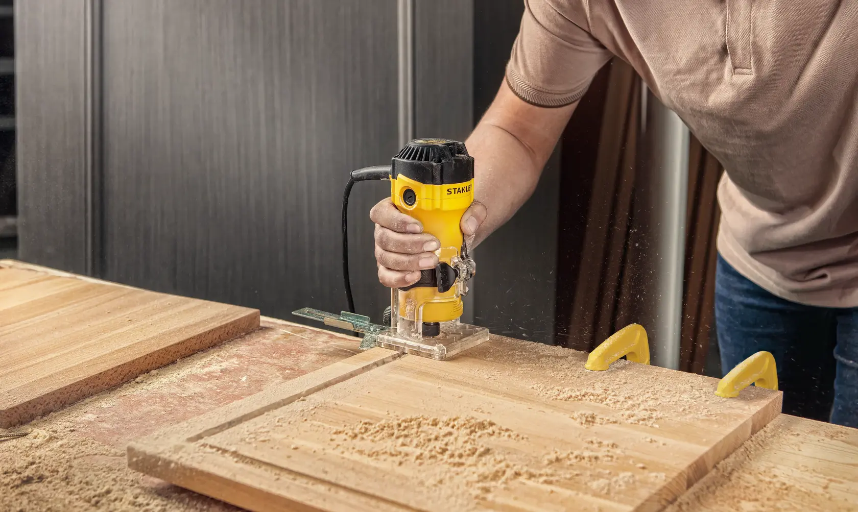 STANLEY ST55-B2 woodworking router used on a wooden board, yellow body, workshop setting.