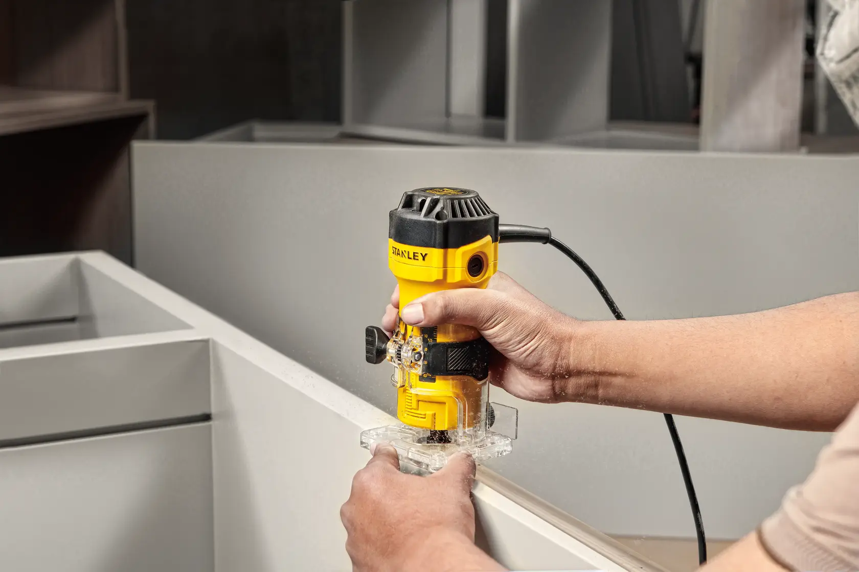 Photo of STANLEY ST55-B2 handheld electric trimmer being used on a cabinet edge, yellow and black color.