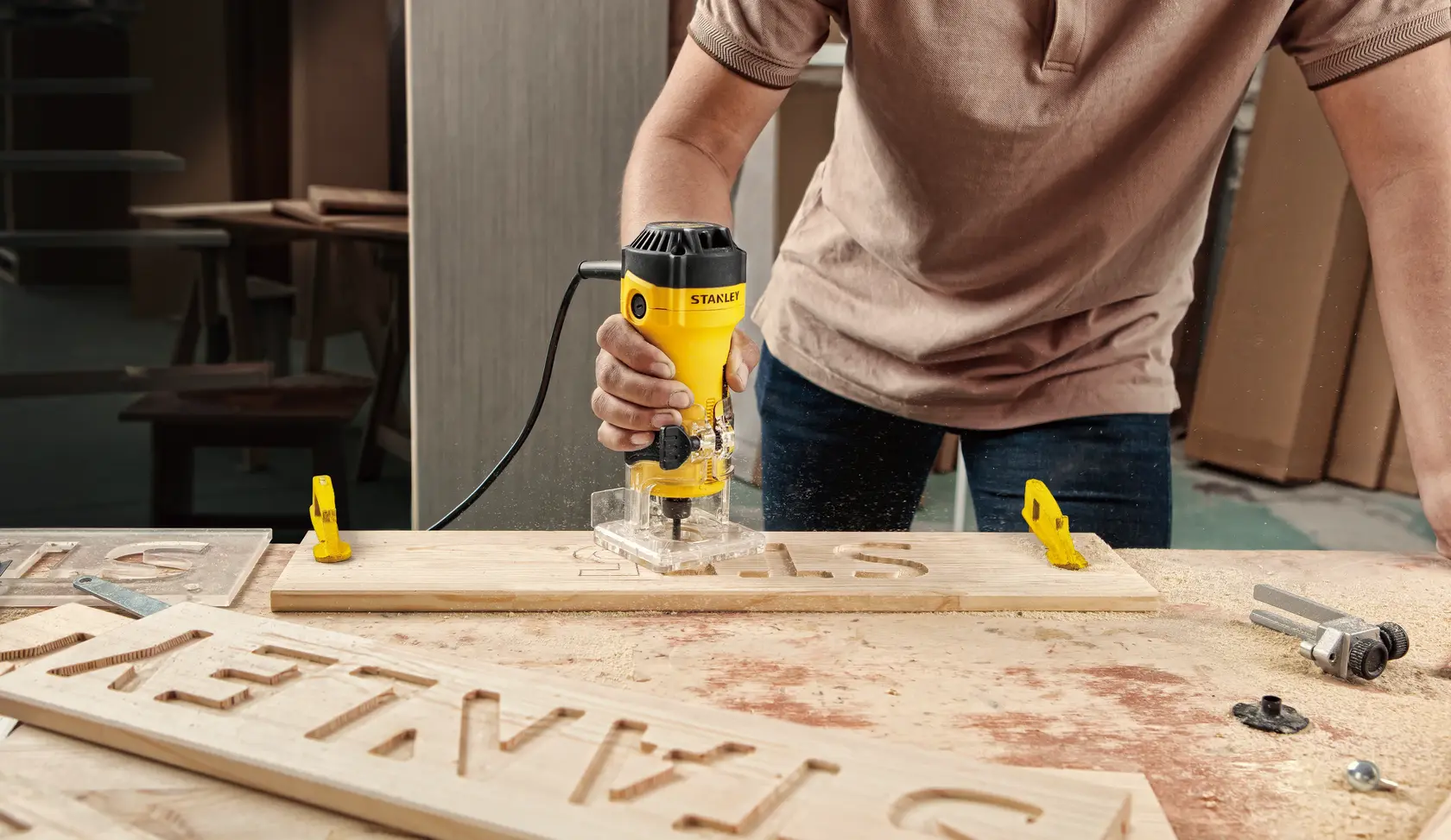 STANLEY ST55-B2 router used to carve letters into wood in a workshop setting.