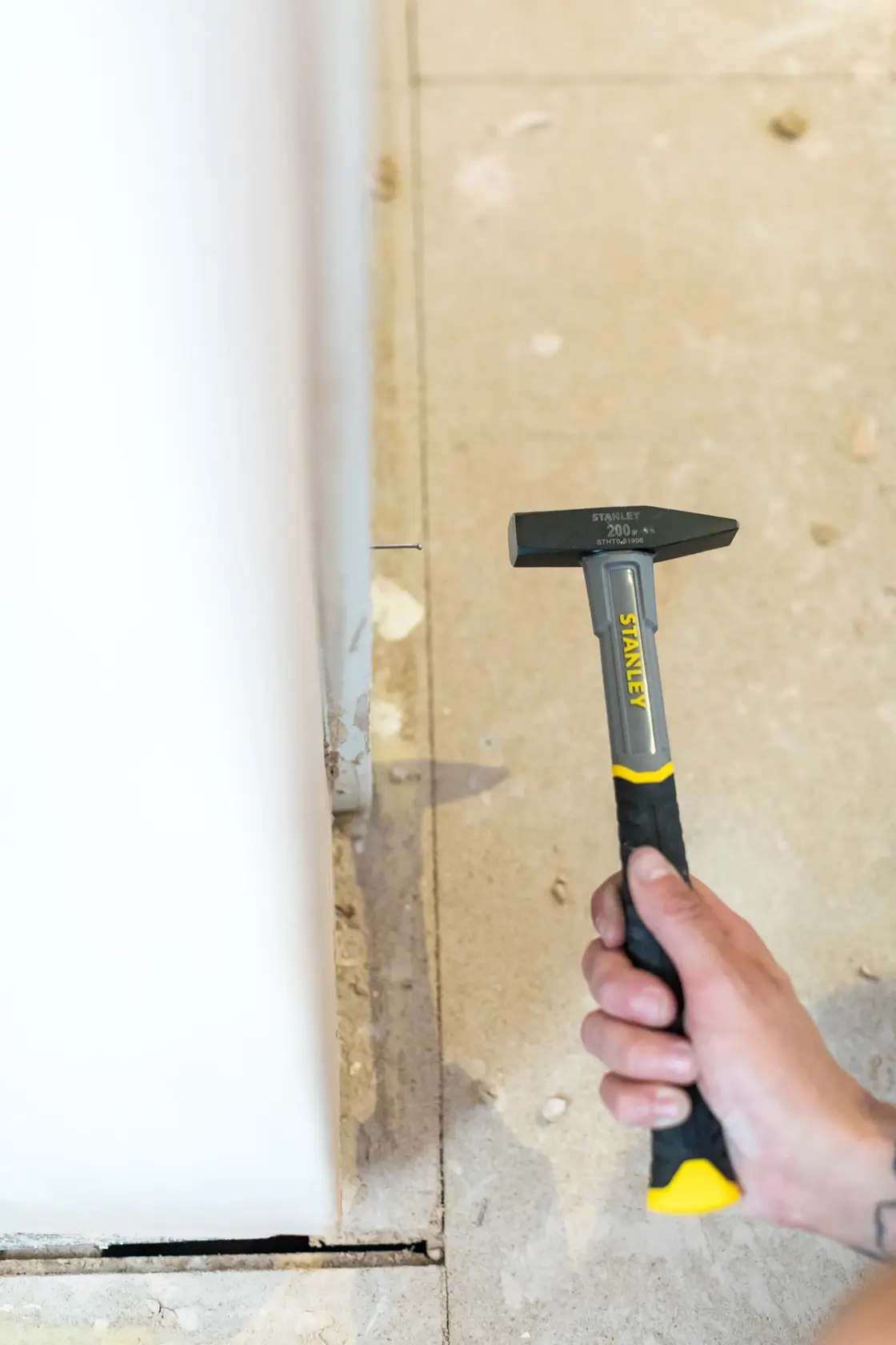 STANLEY STHT0-51906 hammer with black and yellow handle held in hand, indoor construction setting.