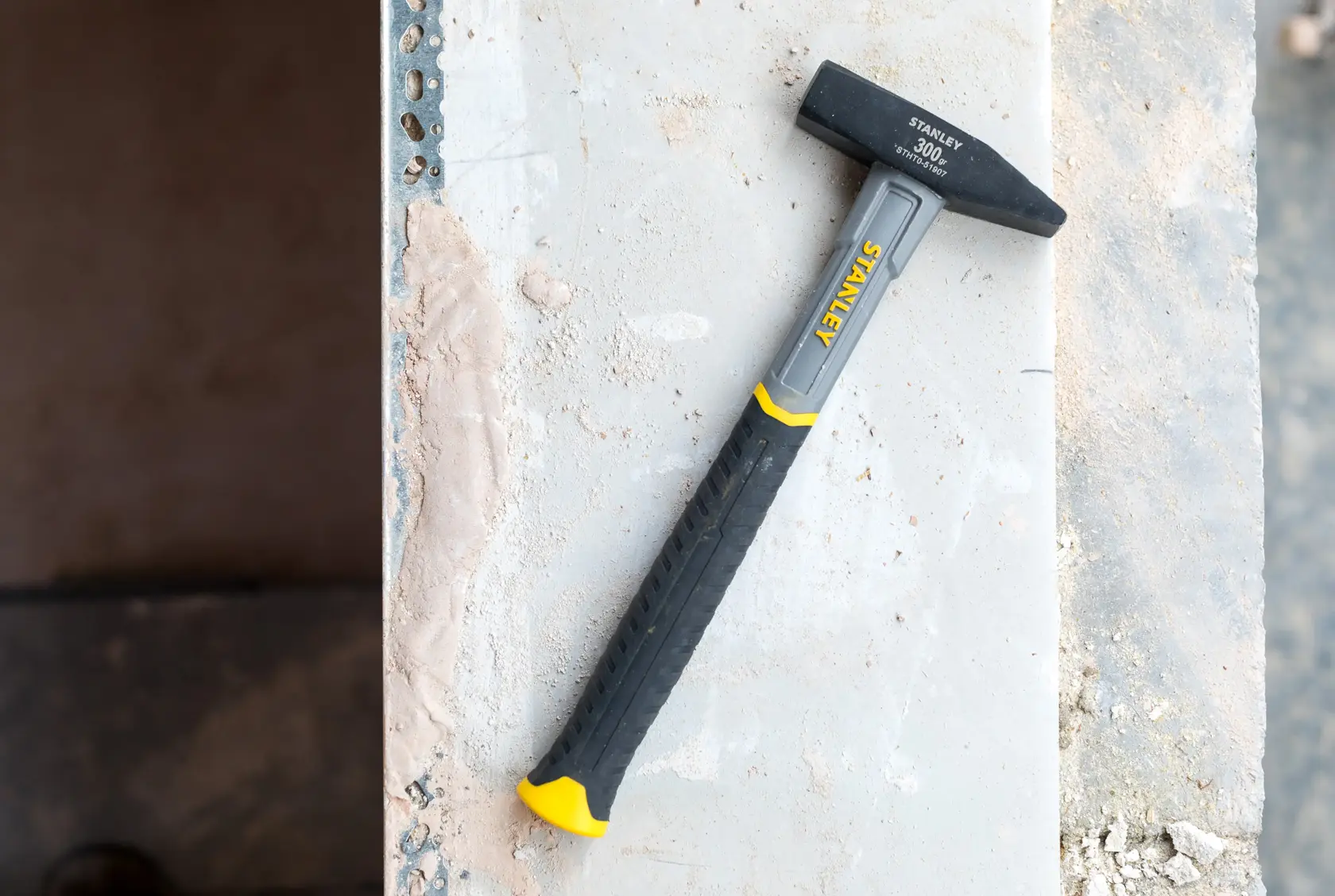 Photo of STANLEY STHT0-51907 club hammer with black and yellow handle on a construction surface.