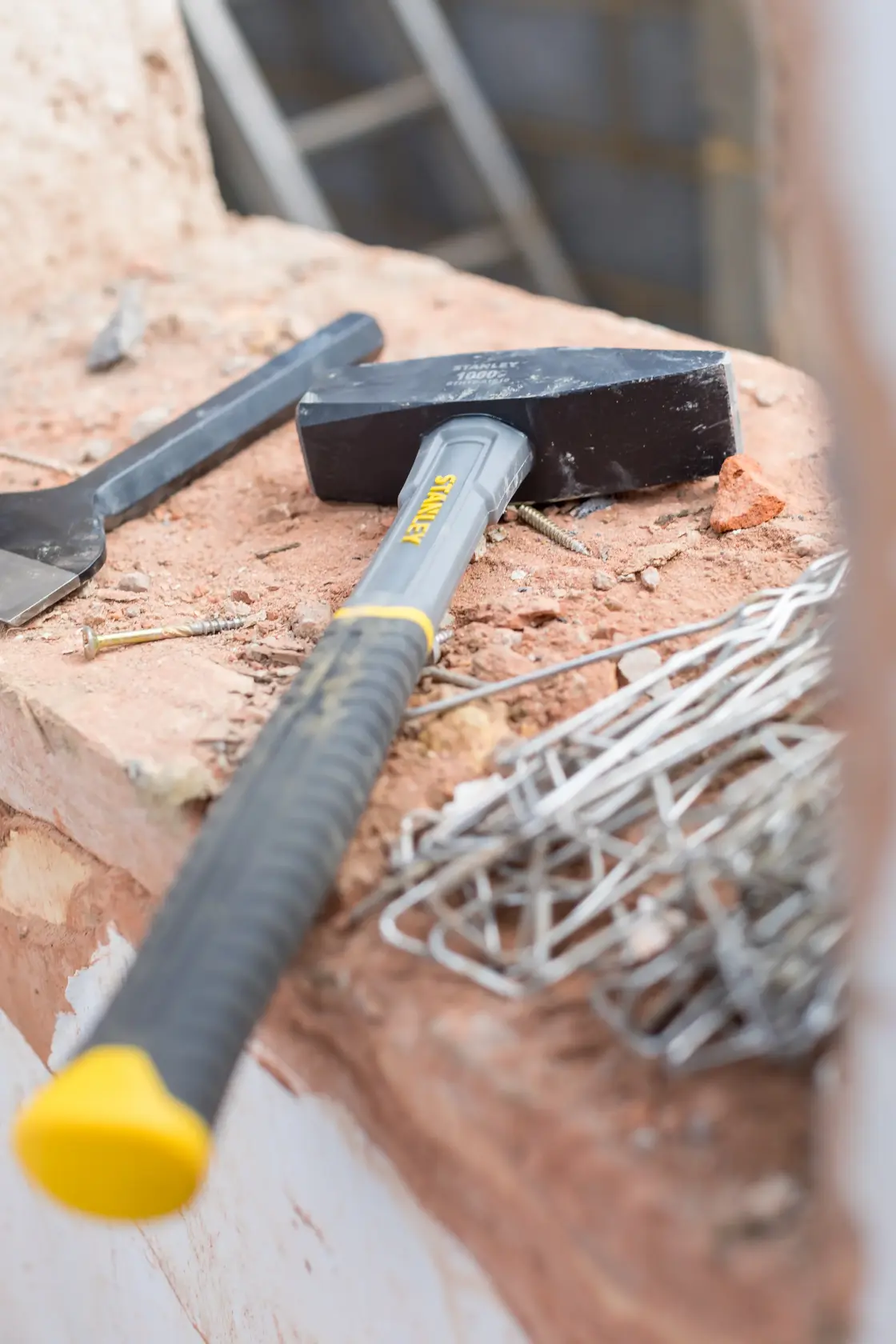 STANLEY STHT0-51910 sledge hammer with black head and yellow-gray handle on construction site.