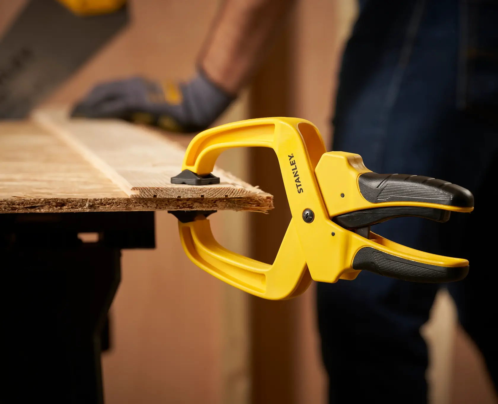 STANLEY STHT0-83200 spring clamp holding wood on workbench, close-up during woodworking.