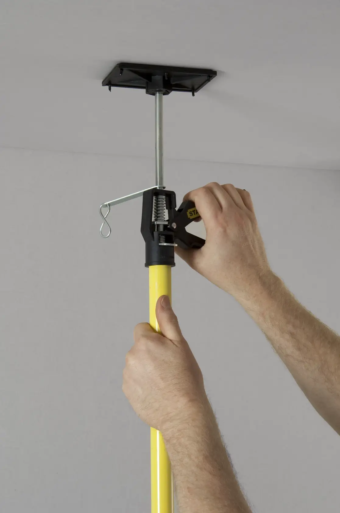 STANLEY STHT1-05932 telescopic drywall support pole shown being adjusted against ceiling.