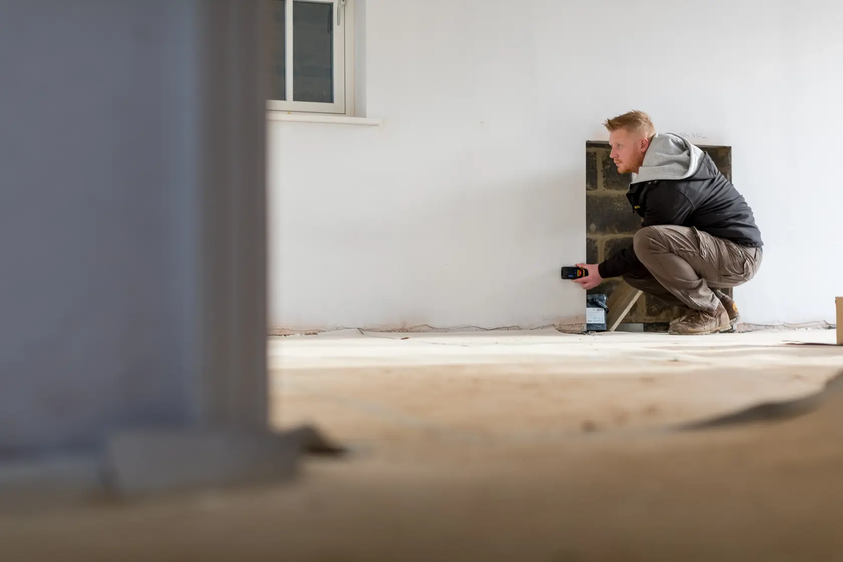 STANLEY STHT1-77139 laser distance measurer in use for measuring a wall in a room during construction.