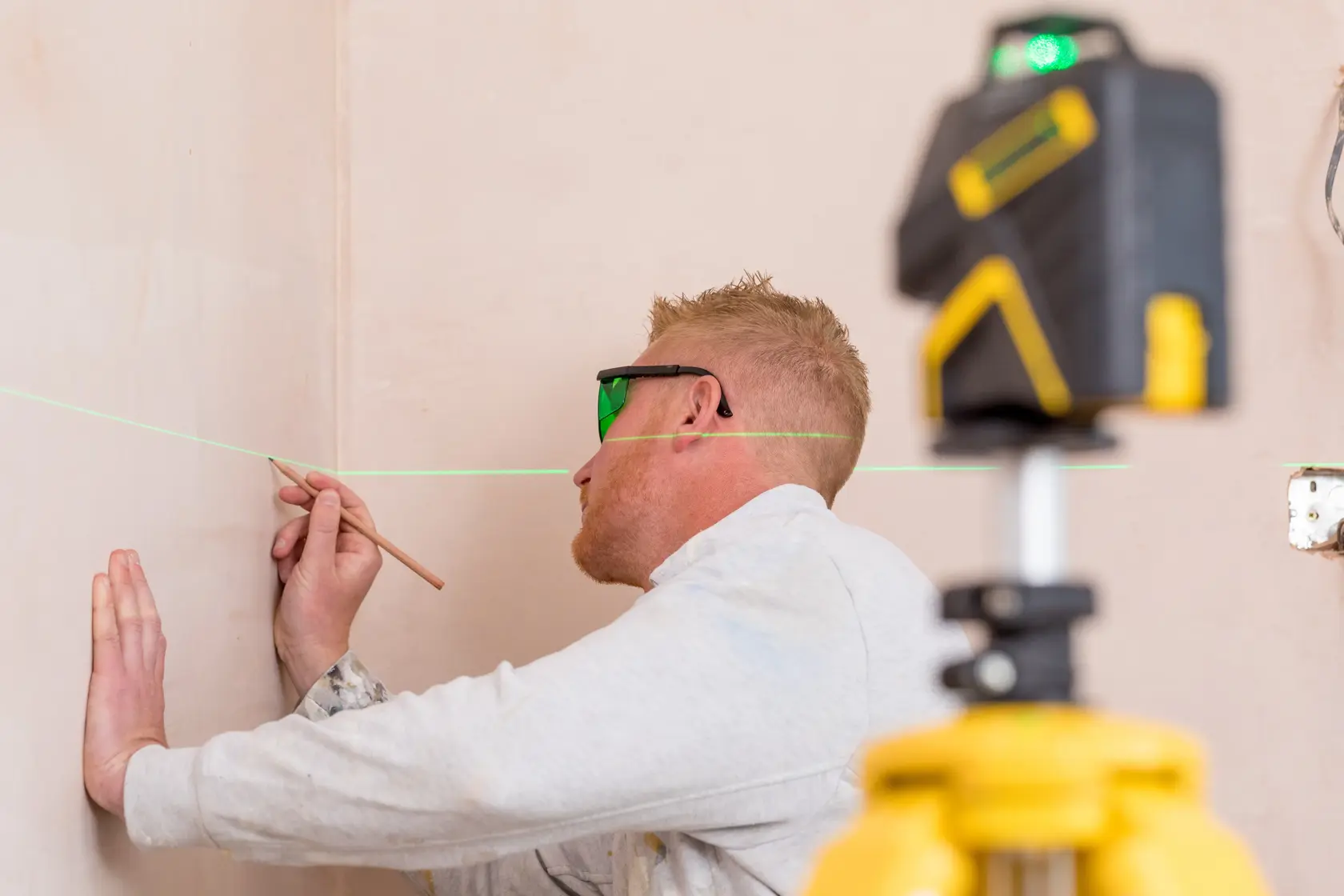 Photo of STANLEY STHT1-77367 laser level projecting green line, used by person marking wall, photography category.