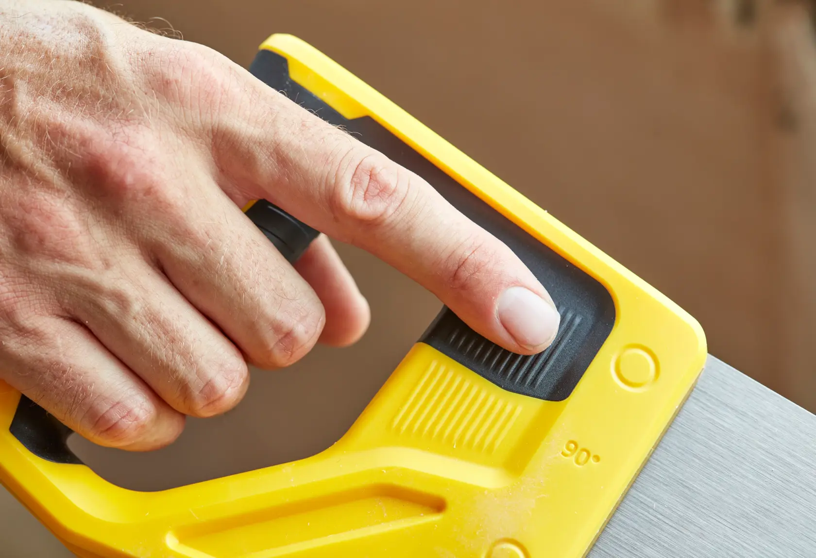 STANLEY STHT20351-1 hand saw, close-up of yellow handle and adjustment grip held by a finger.