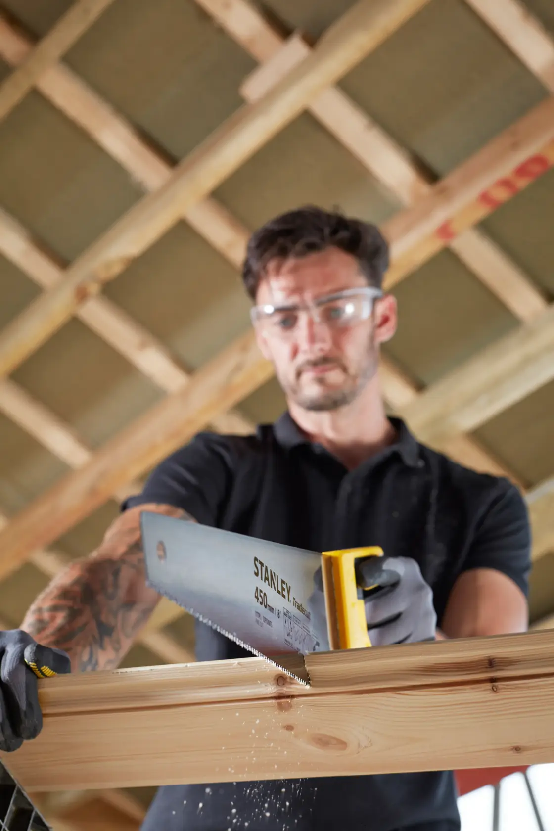 Photo of STANLEY STHT20355-1 handsaw with yellow handle, cutting wood beam indoors.
