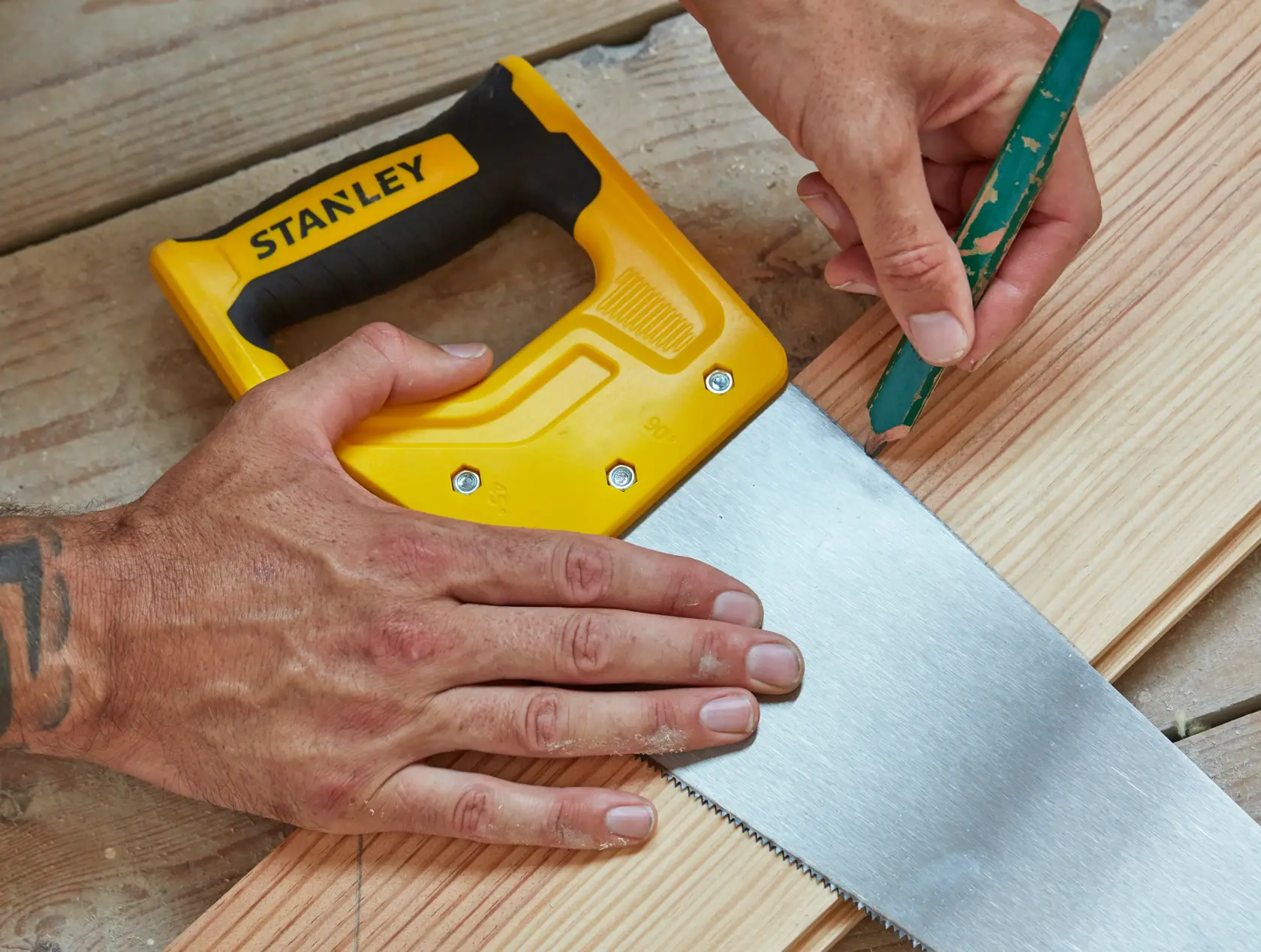 Photo of STANLEY STHT20370-1 hand saw with yellow handle used on wooden planks, top view.