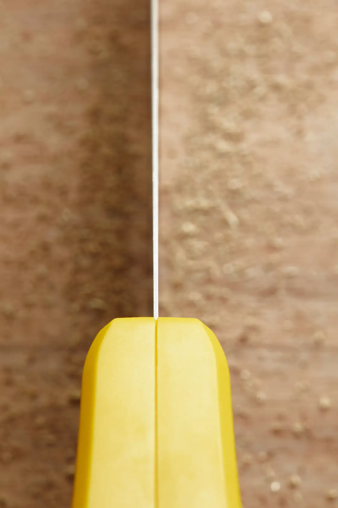STANLEY STHT20370-1 hand saw close-up, yellow handle and blade, vertical angle on wooden surface.