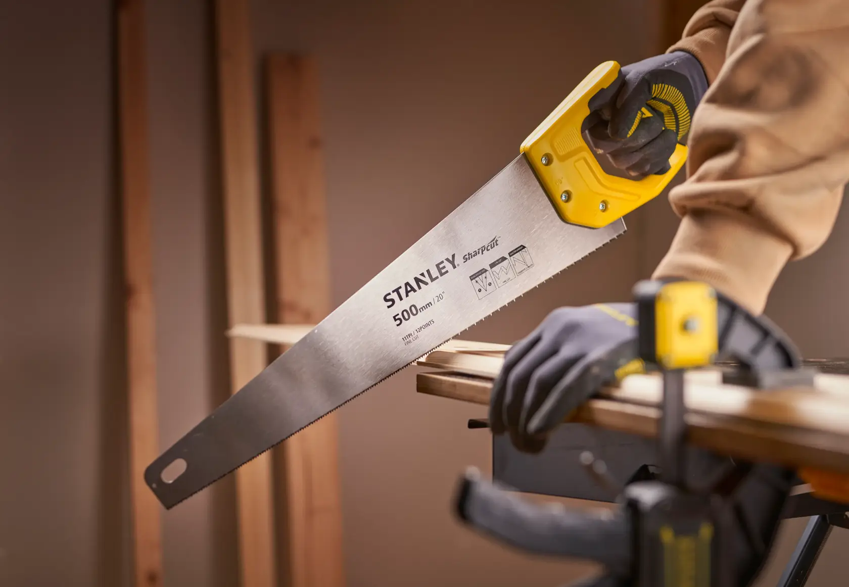 Photo of STANLEY STHT20371-1 handsaw with yellow handle cutting wood, close-up side view.