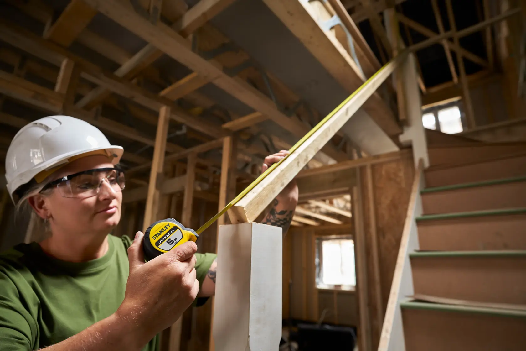 STANLEY® CONTROL-LOCK™ 5M (25mm wide) Tape Measure being used by worker in extended lock position to measure a stair bannister rail