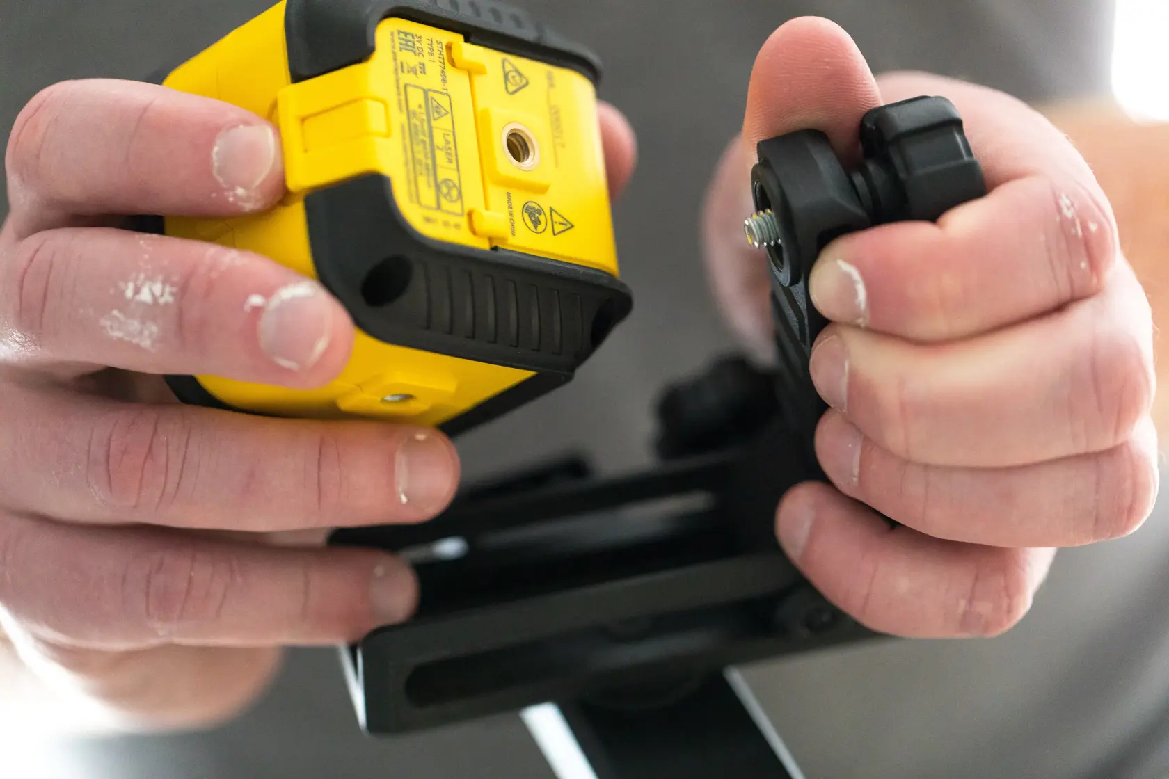 Stanley STHT77499-1 photography of a close-up hand holding a laser level and mounting bracket.