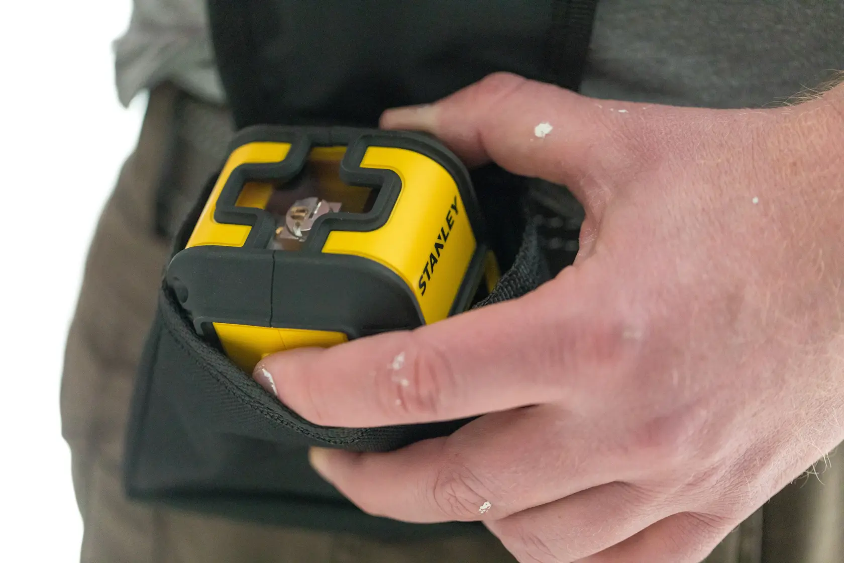 Photo of STANLEY STHT77499-1 yellow and black laser level being placed in a tool pouch.