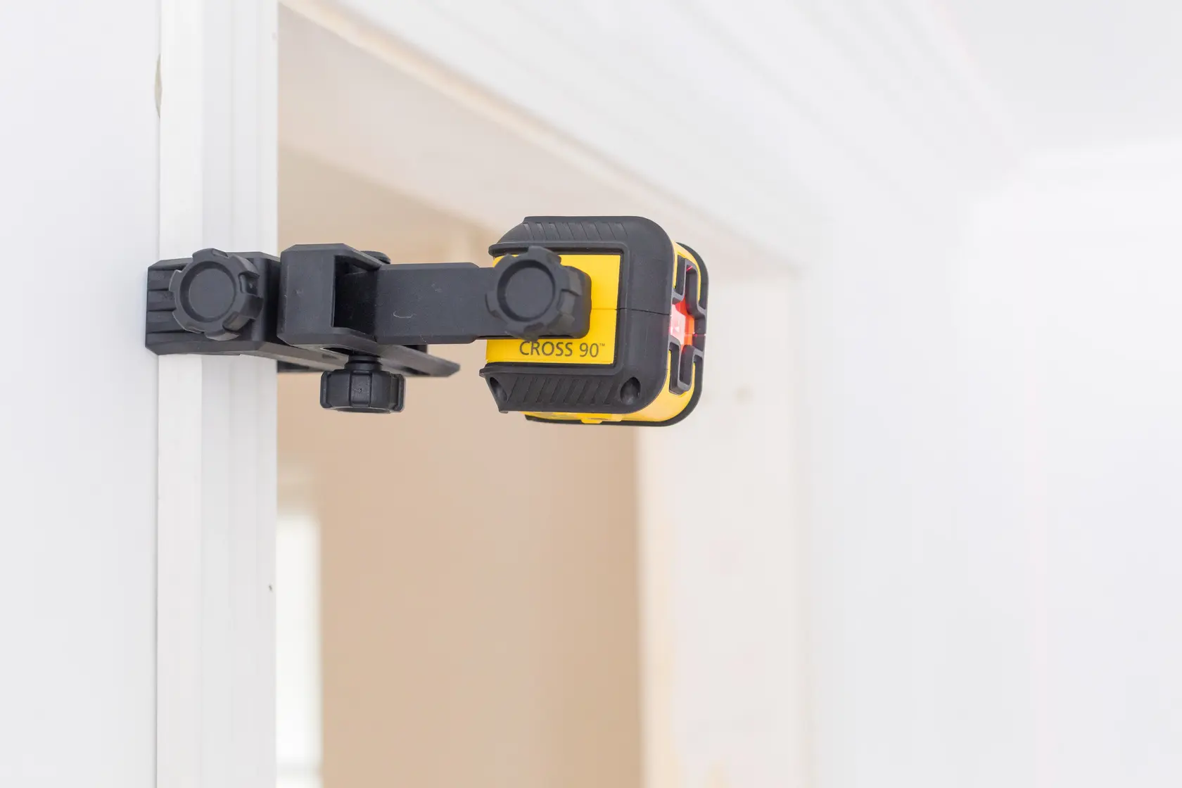 STANLEY STHT77502-1 laser level tool with clamp attached to a door frame, side angle, yellow and black color.