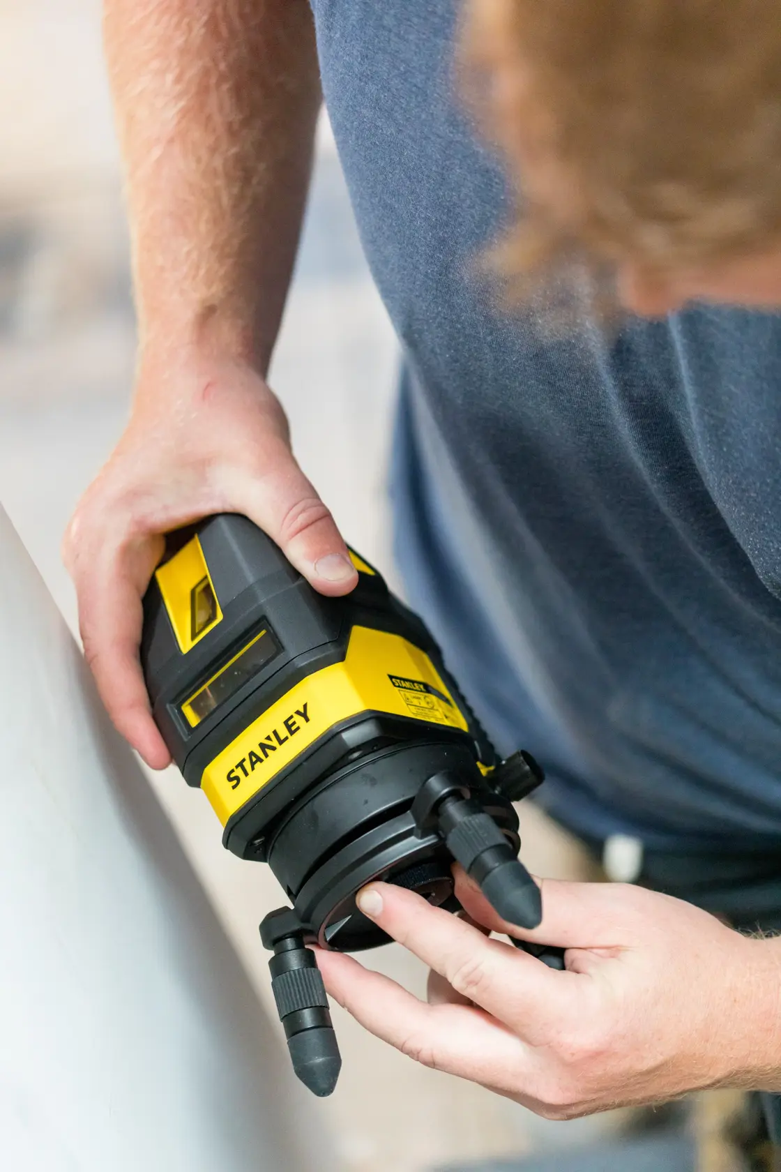 STANLEY STHT77514-1 laser level in use, black and yellow body, shown from above during adjustment.