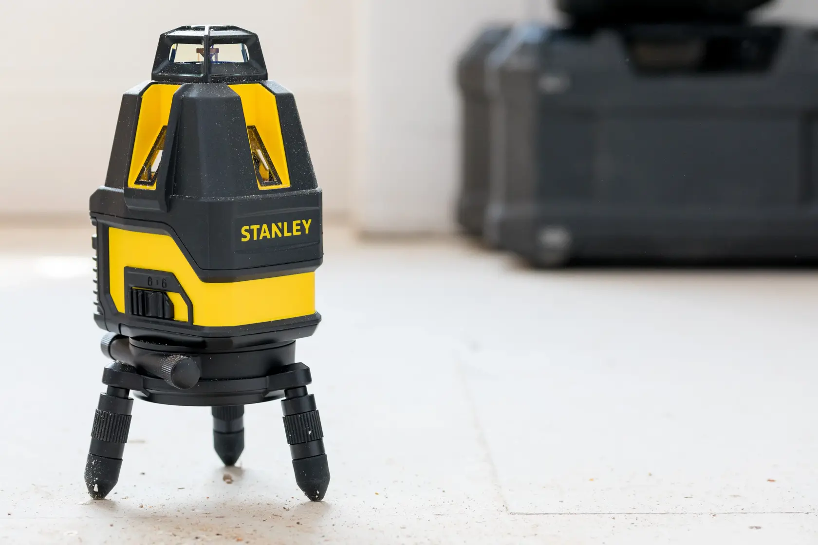 STANLEY STHT77524-1 laser level on tripod, yellow and black, indoor setting, product photography.